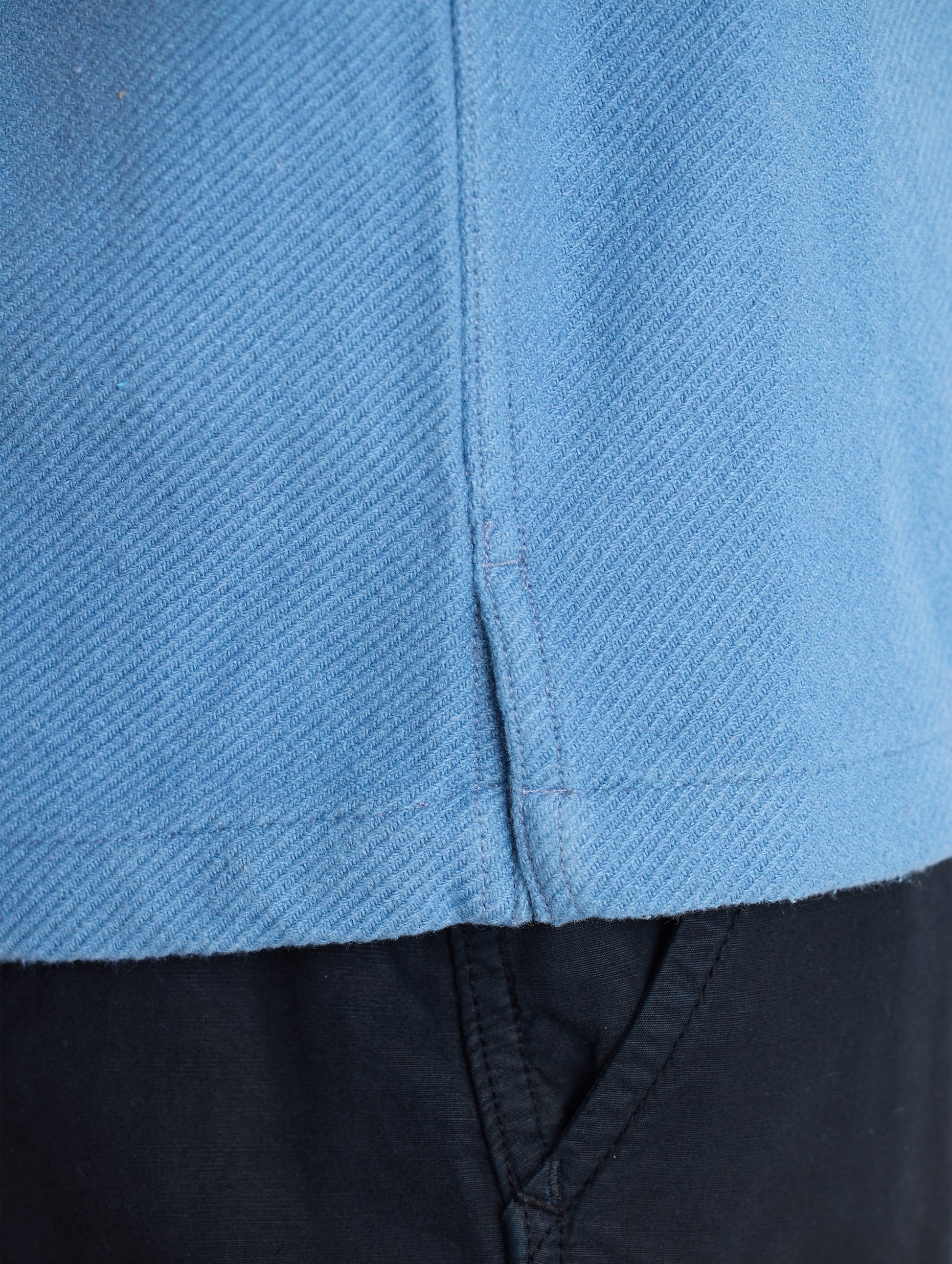 Closeup detailed view of the on-seam side slits on the Pioneer Heavyweight Button-Down in Portal Blue from AETHER Apparel.
