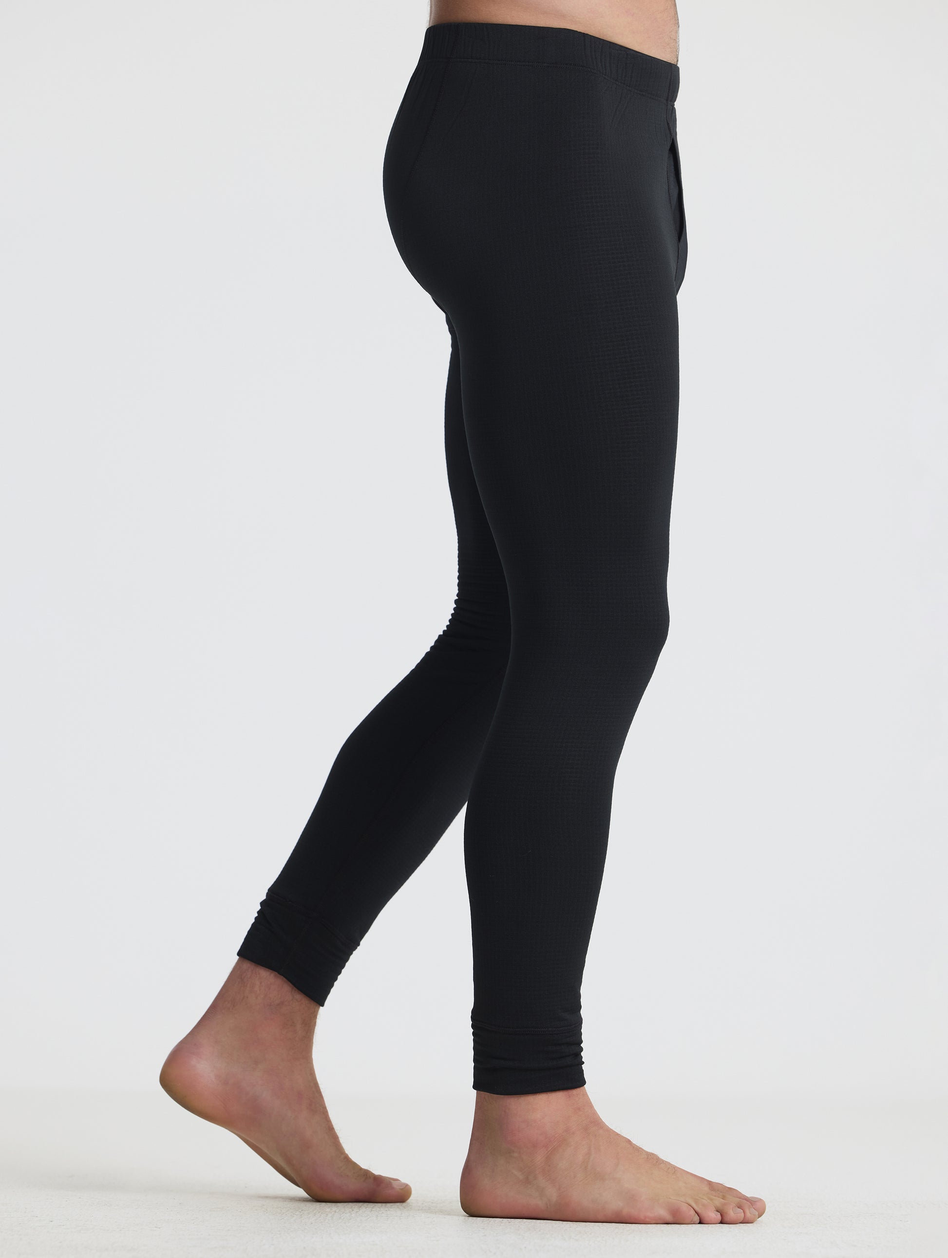Side profile lower-body view of man wearing the Polar Base Layer Pant in Onyx Black from AETHER Apparel.