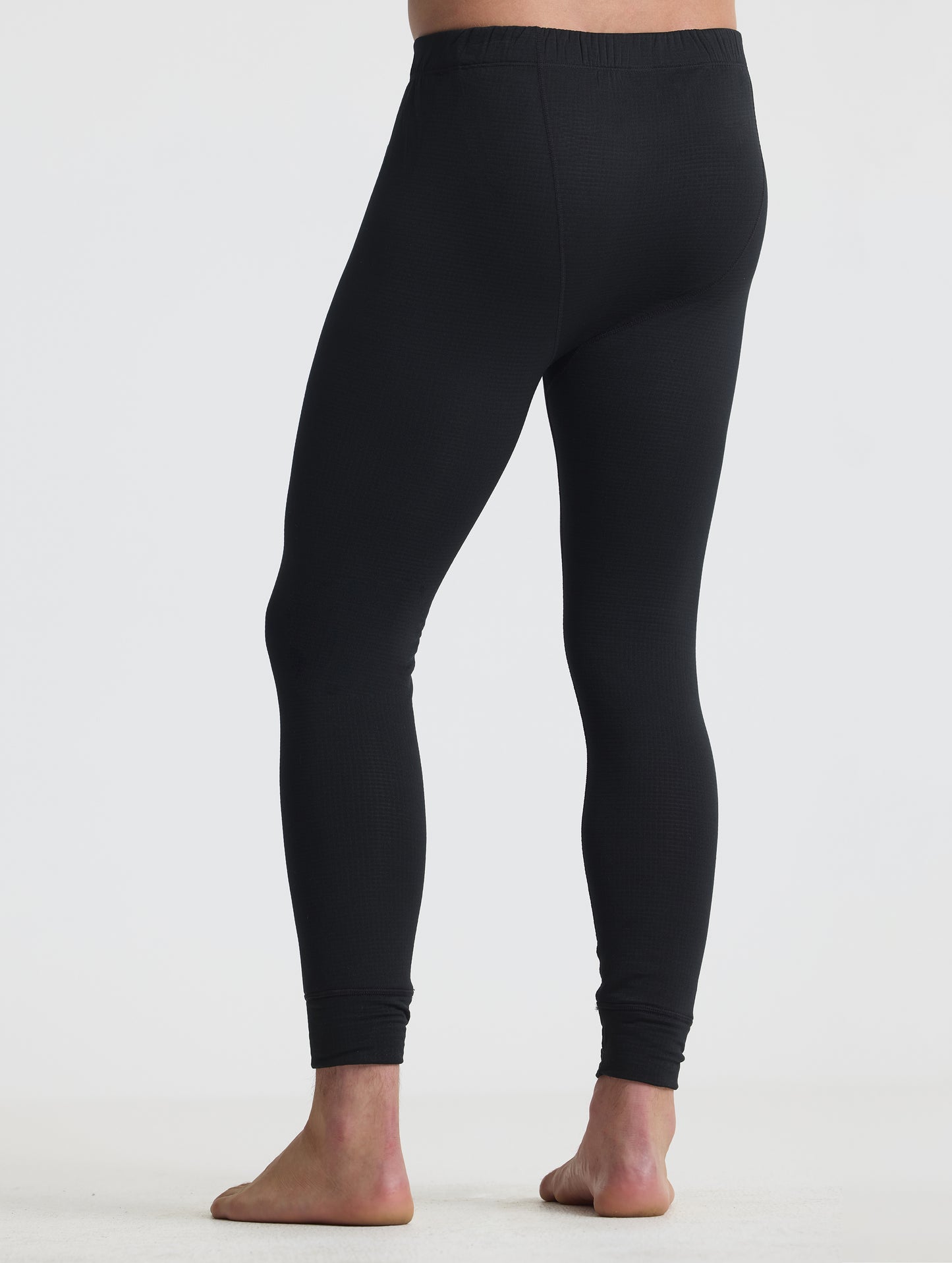 Rear angled lower-body view of man wearing the Polar Base Layer Pant in Onyx Black from AETHER Apparel.