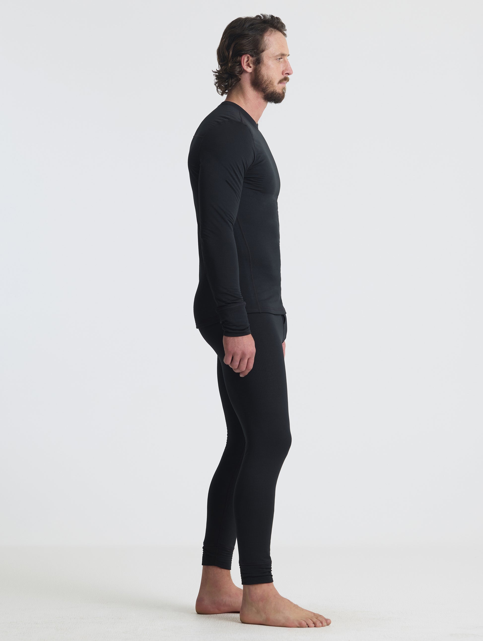Side profile full-body view of man wearing the Polar Base Layer Pant in Onyx Black from AETHER Apparel.