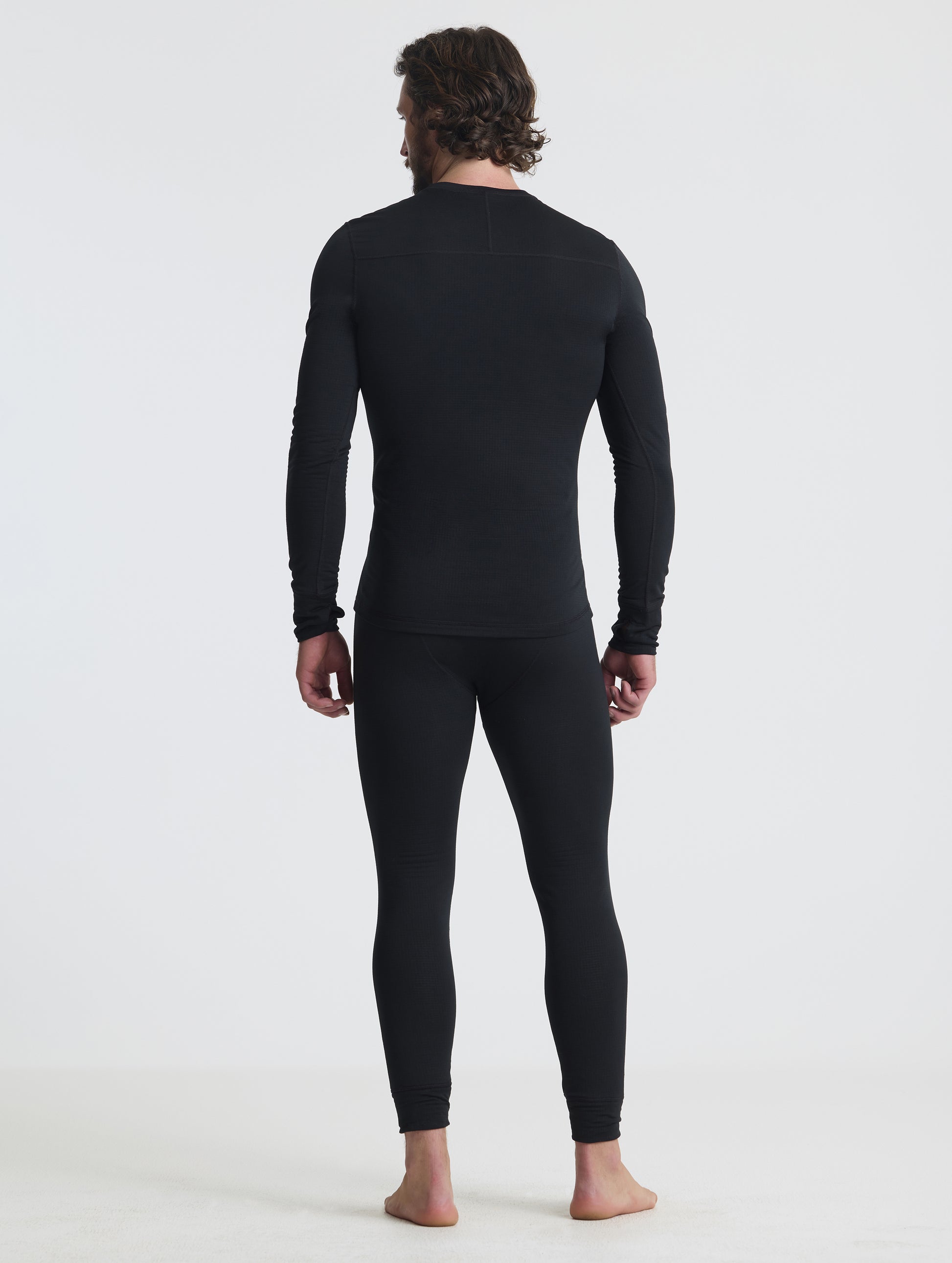 Rear full-body view of man wearing the Polar Base Layer Pant in Onyx Black from AETHER Apparel.