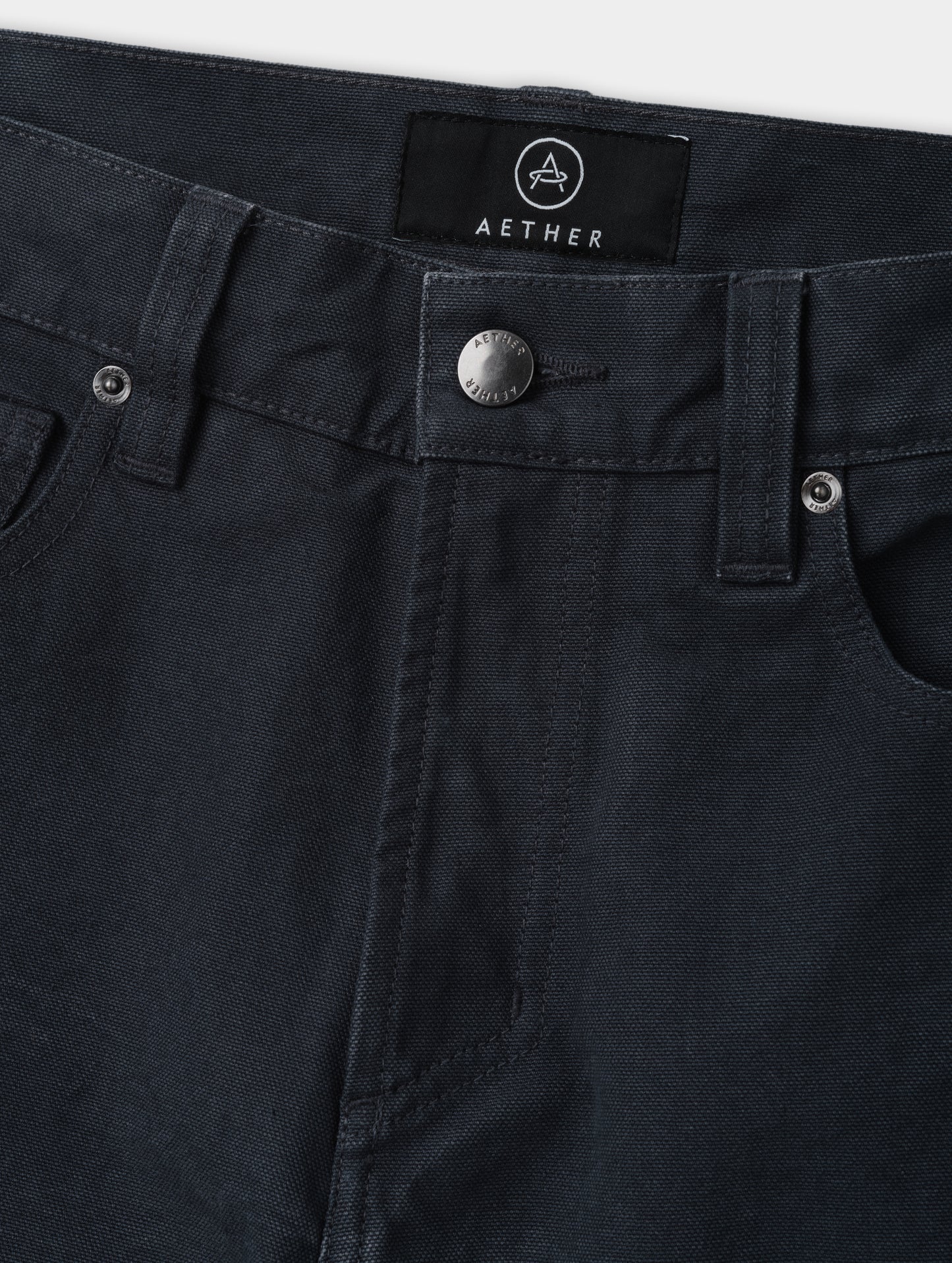 Closeup detailed view of the zippered fly and metal shank button closure on the Porter 5-Pocket Pant in Graphite from AETHER Apparel.