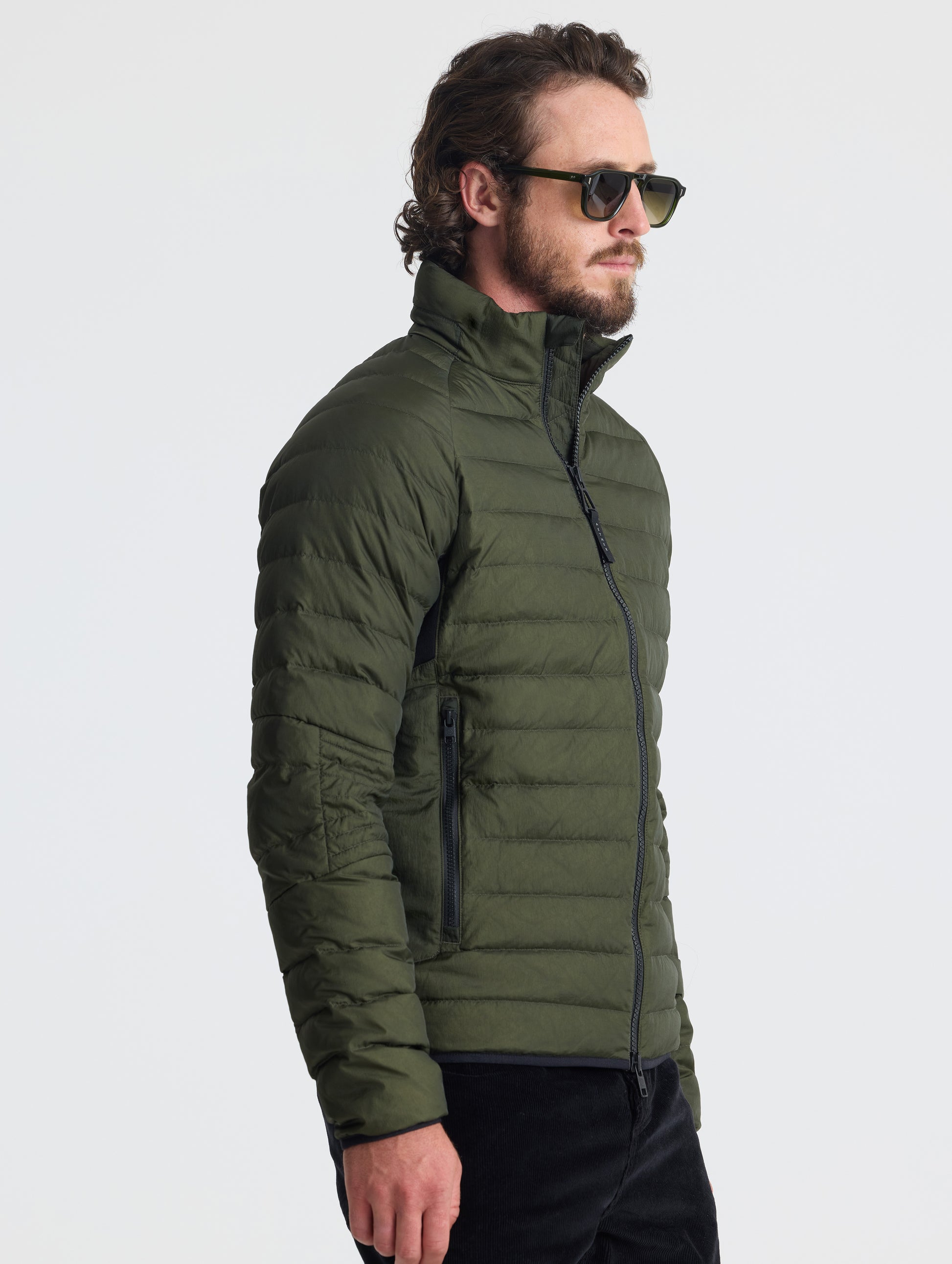 Angled view of man wearing Prospect Packable Down Jacket in Forest Green from AETHER Apparel.