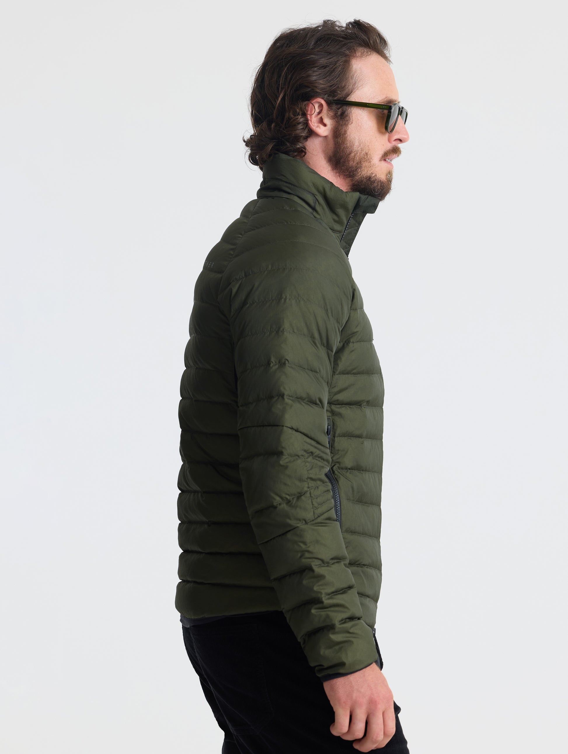 Right profile of man wearing Prospect Packable Down Jacket in Forest Green from AETHER Apparel.