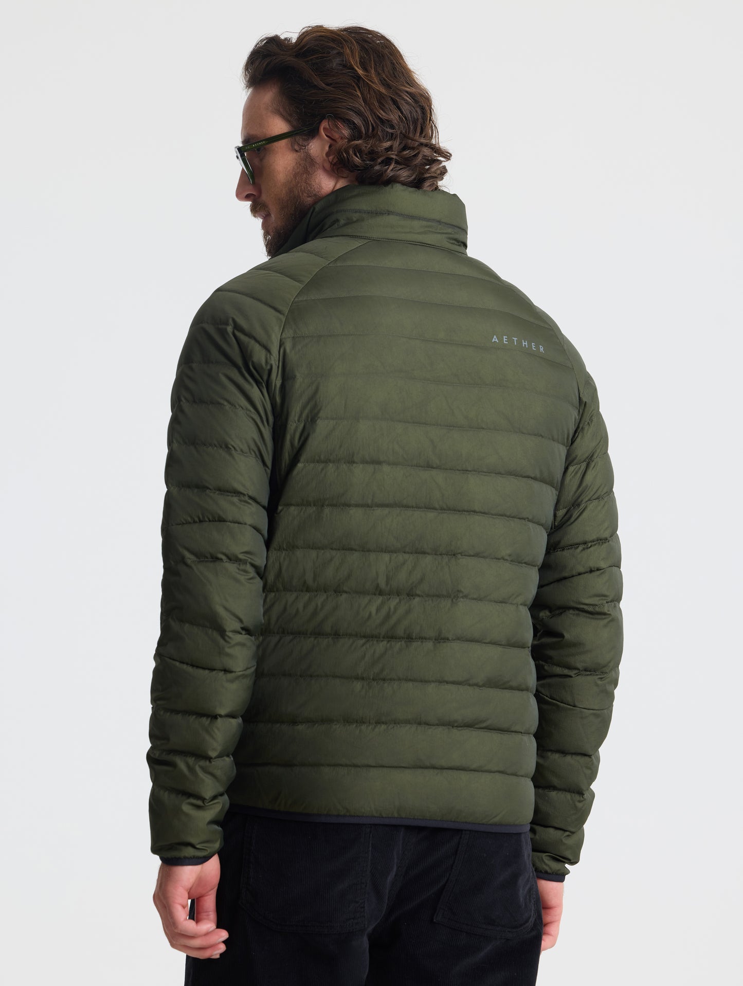 Rear view of man wearing Prospect Packable Down Jacket in Forest Green from AETHER Apparel.
