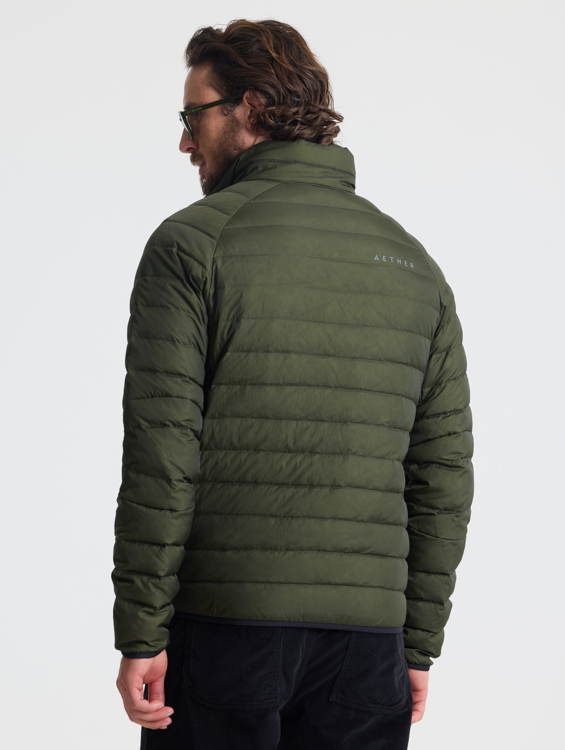 Rear view of man wearing Prospect Packable Down Jacket in Forest Green from AETHER Apparel.