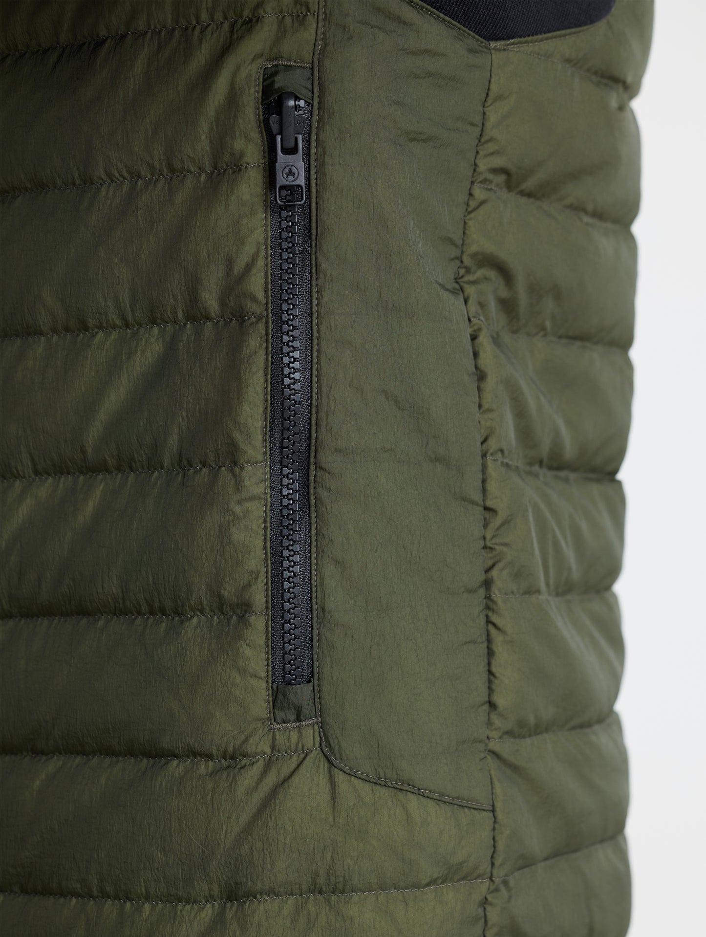 Closeup view of wearer's left zipped hand pocket of Prospect Packable Down Jacket in Forest Green from AETHER Apparel.