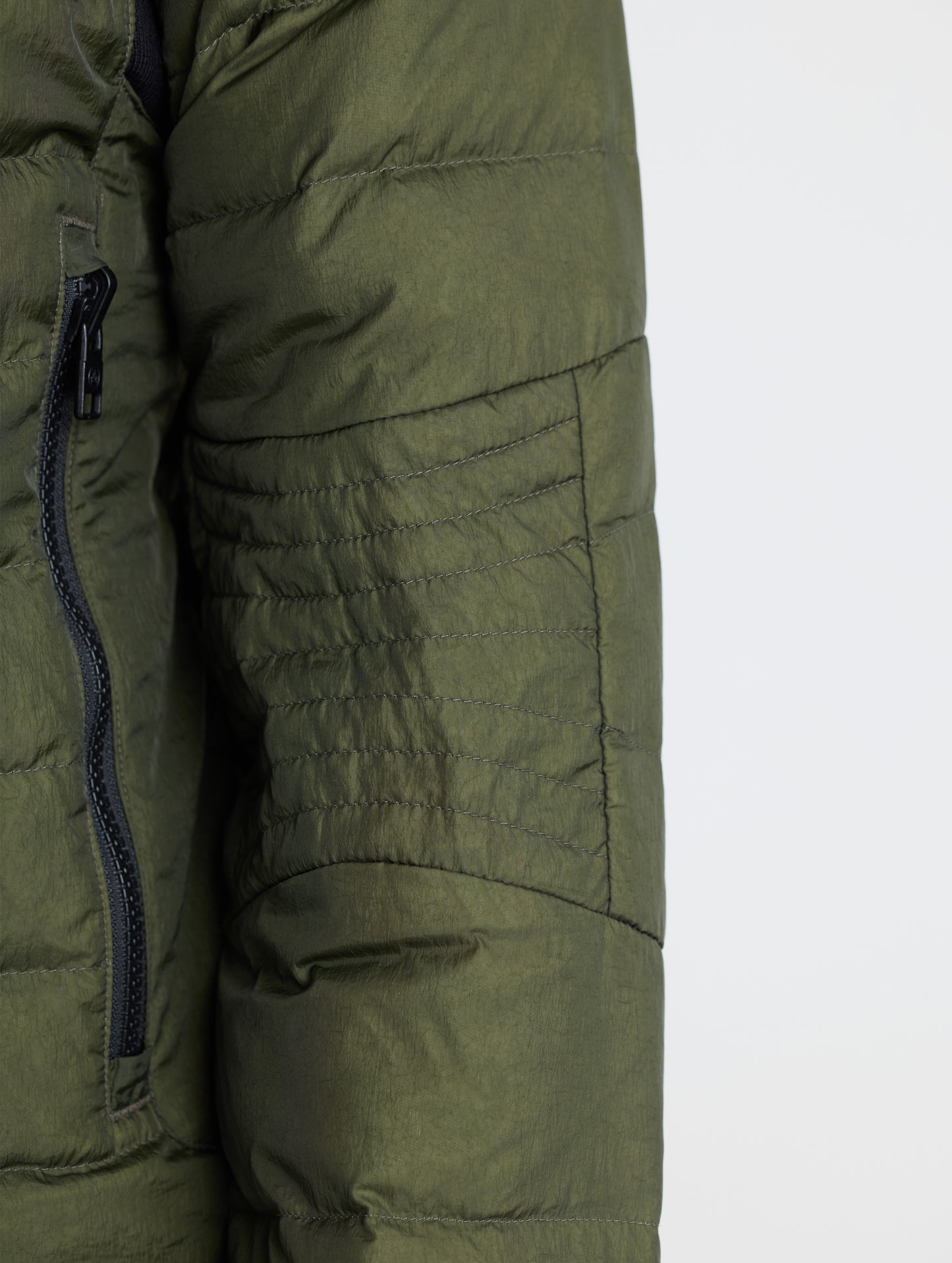 Closeup view of wearer's left sleeve of Prospect Packable Down Jacket in Forest Green from AETHER Apparel.