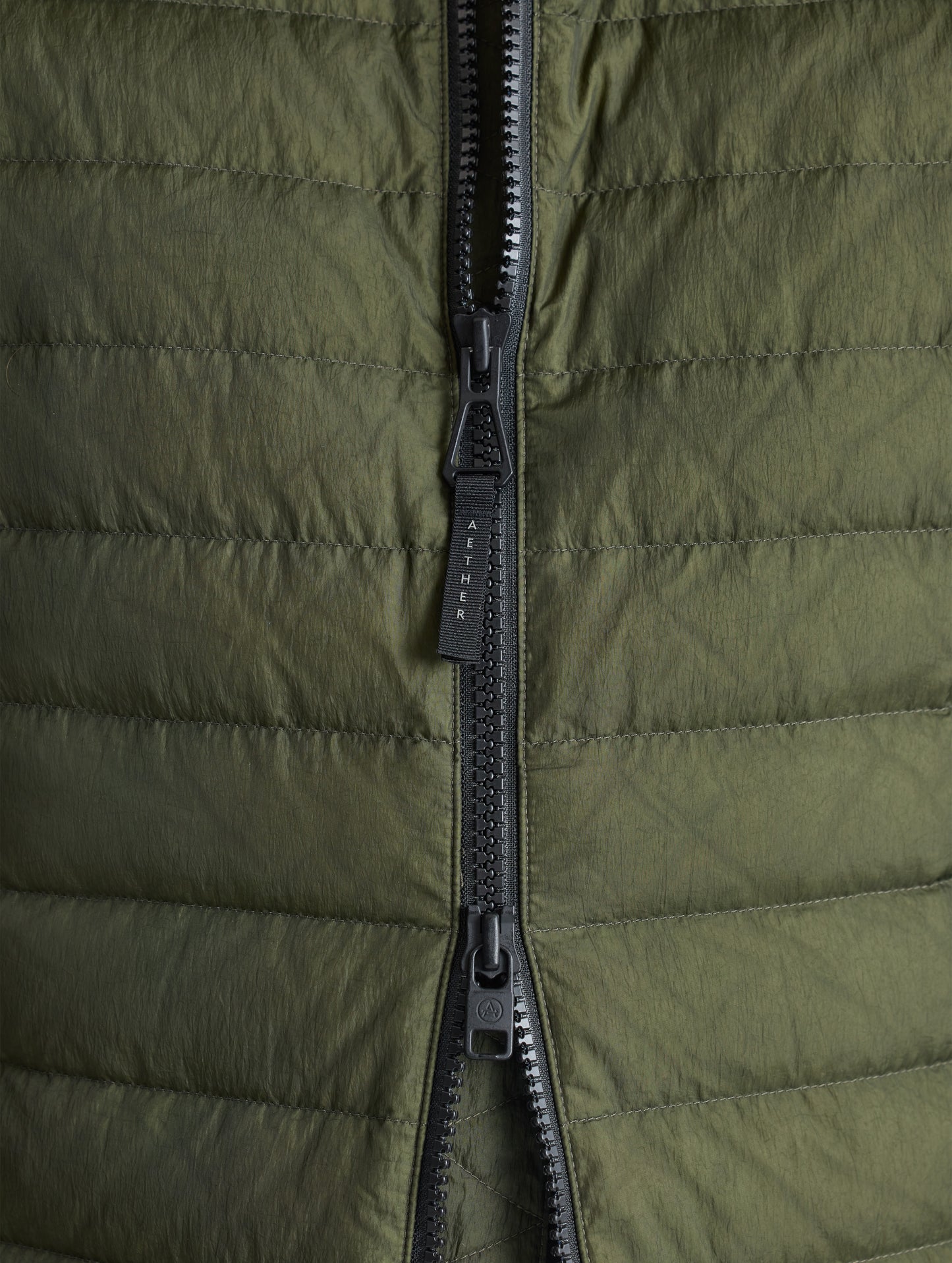 Closeup view of front zipper of Prospect Packable Down Jacket in Forest Green from AETHER Apparel.
