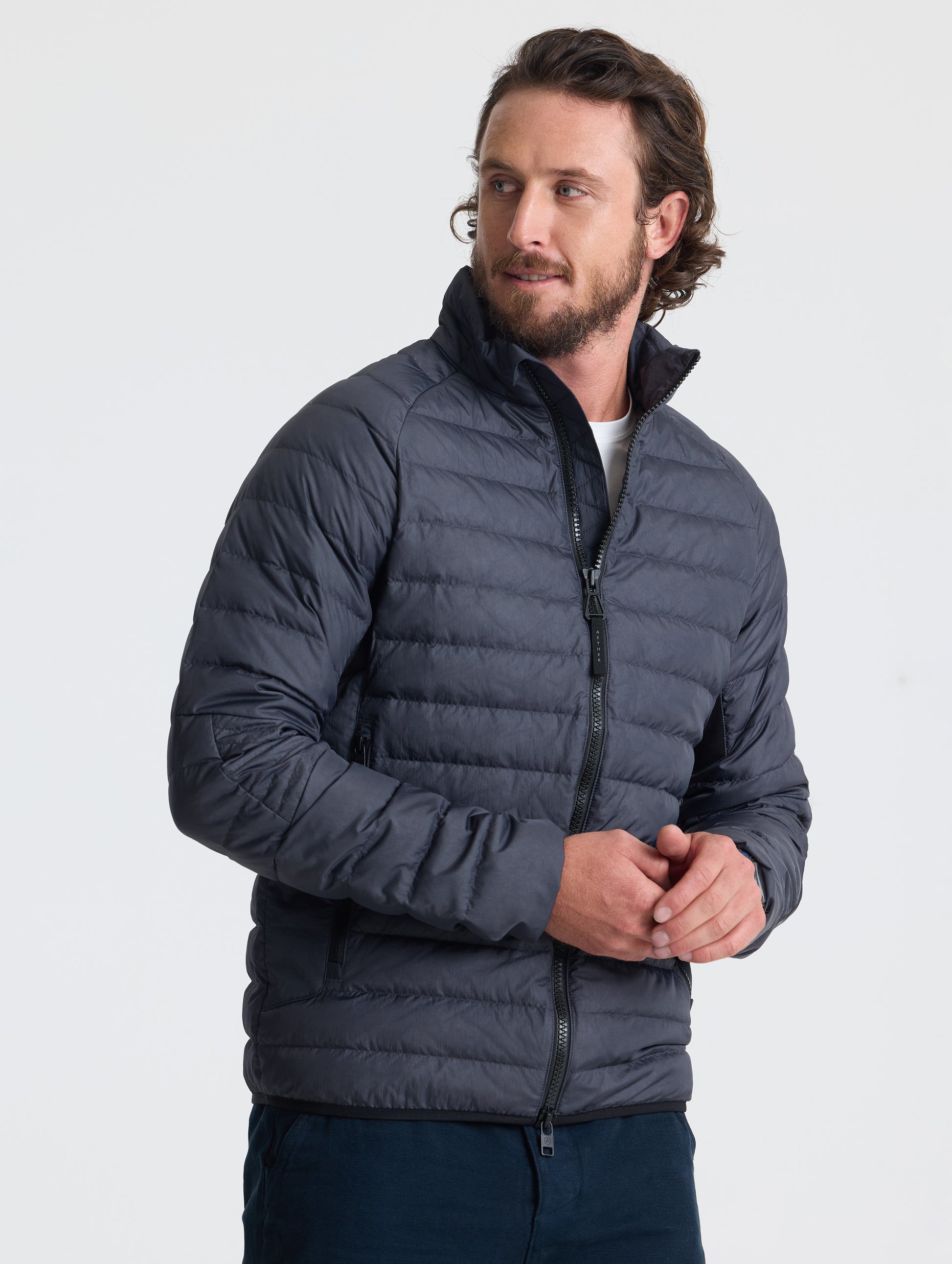 Angled view of man wearing Prospect Packable Down Jacket in Onyx Black from AETHER Apparel.