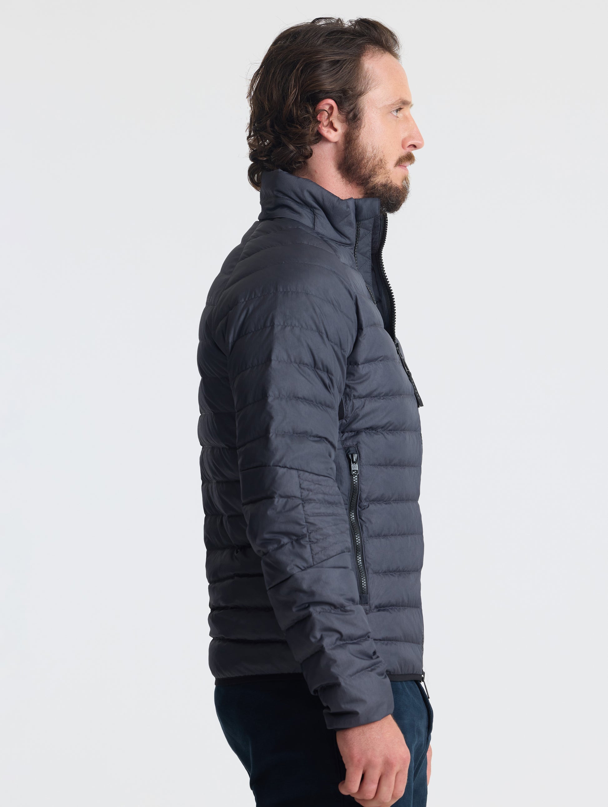 Right profile of man wearing Prospect Packable Down Jacket in Onyx Black from AETHER Apparel.