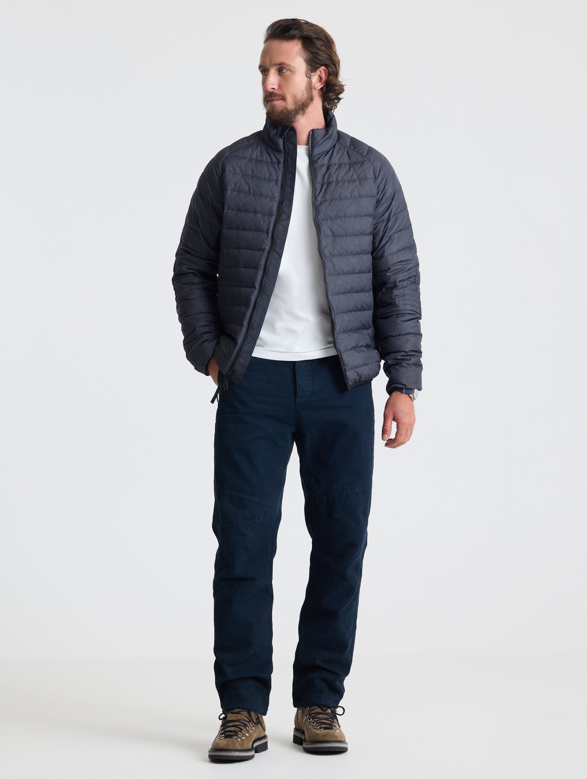 Full body view of man wearing Prospect Packable Down Jacket in Onyx Black from AETHER Apparel.