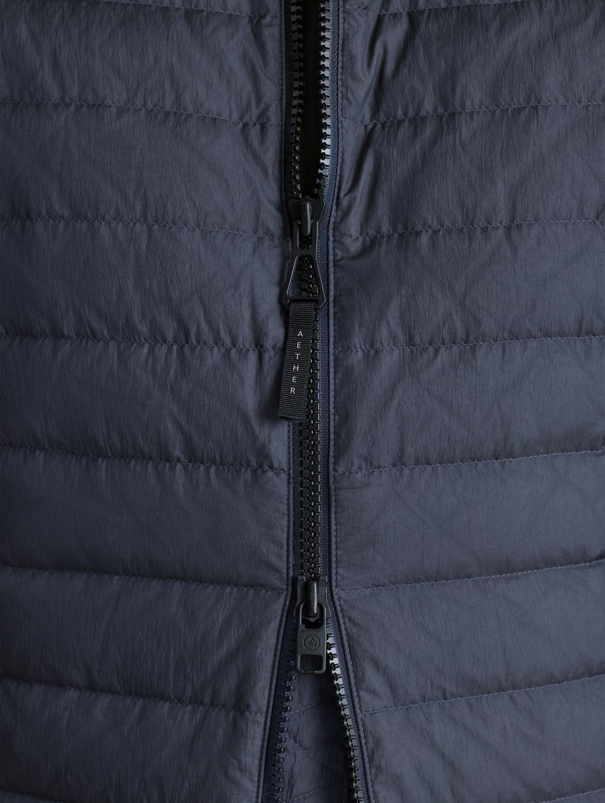 Closeup view of front zipper of Prospect Packable Down Jacket in Onyx Black from AETHER Apparel.