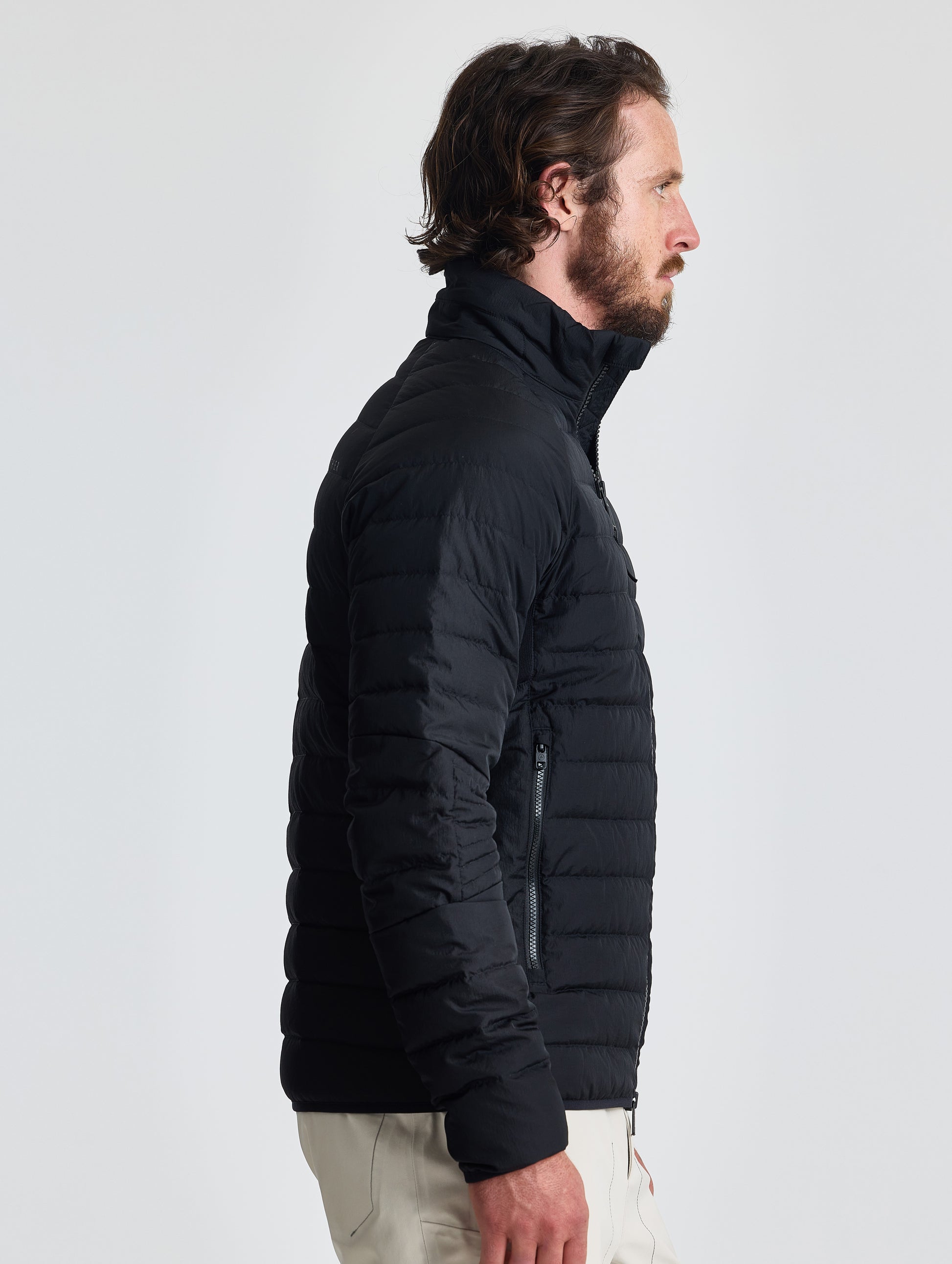 Right profile of man wearing Prospect Packable Down Jacket in Onyx Black from AETHER Apparel.