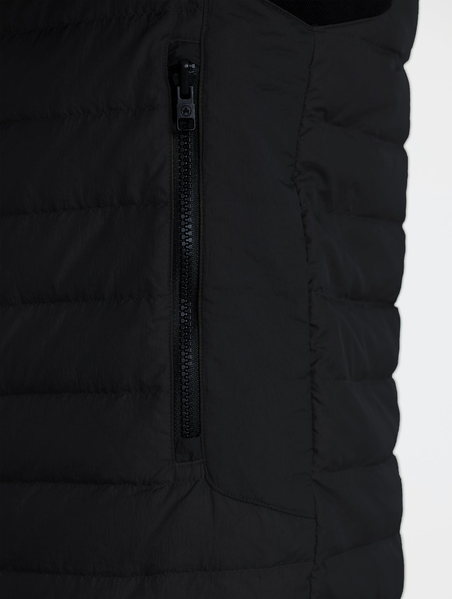 Closeup view of wearer's left zipped hand pocket of Prospect Packable Down Jacket in Onyx Black from AETHER Apparel.