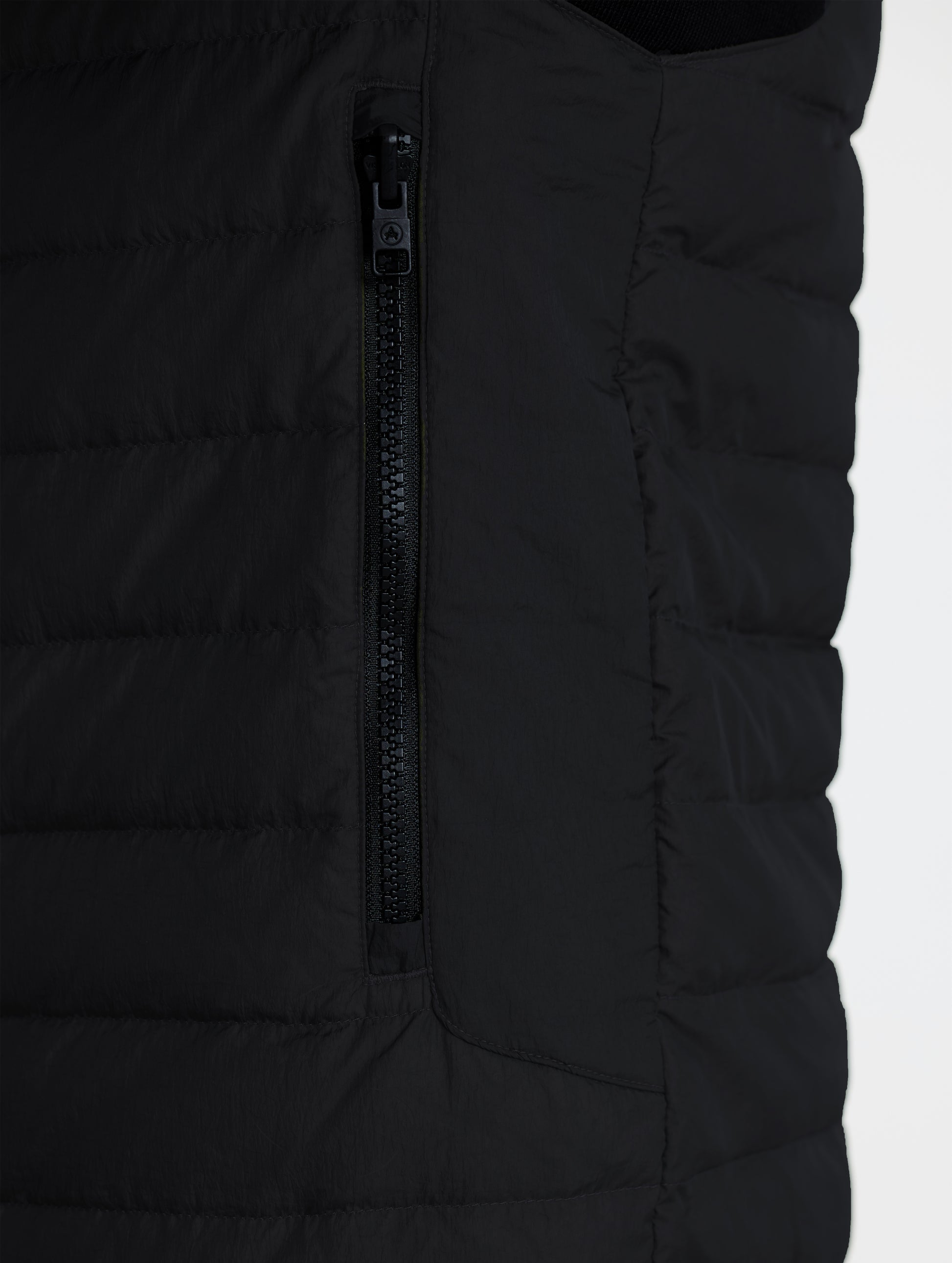 Closeup view of wearer's left zipped hand pocket of Prospect Packable Down Jacket in Onyx Black from AETHER Apparel.