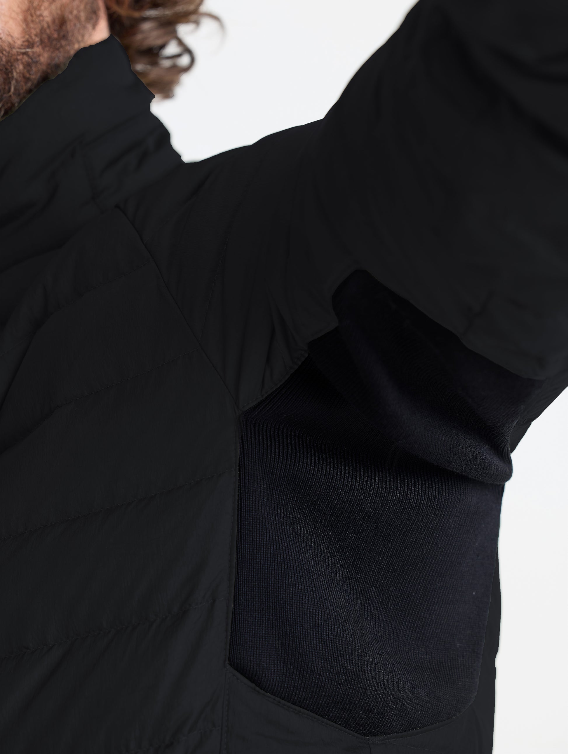 Closeup view of the underarm inset rib knit gussets on the Prospect Packable Down Jacket in Onyx Black from AETHER Apparel.
