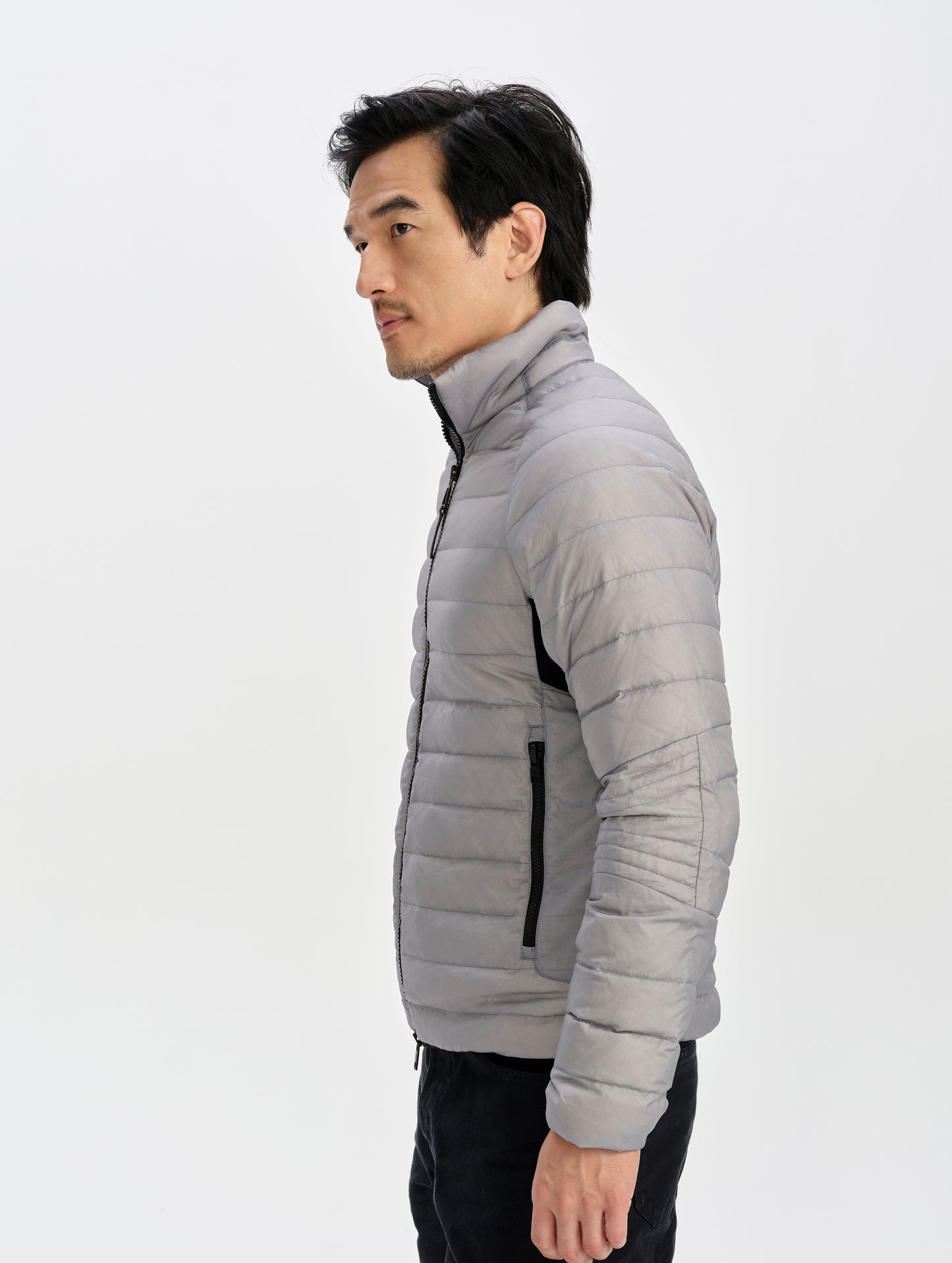 Side profile upper-body view of man wearing Prospect Packable Down Jacket in Sky Grey from AETHER Apparel.