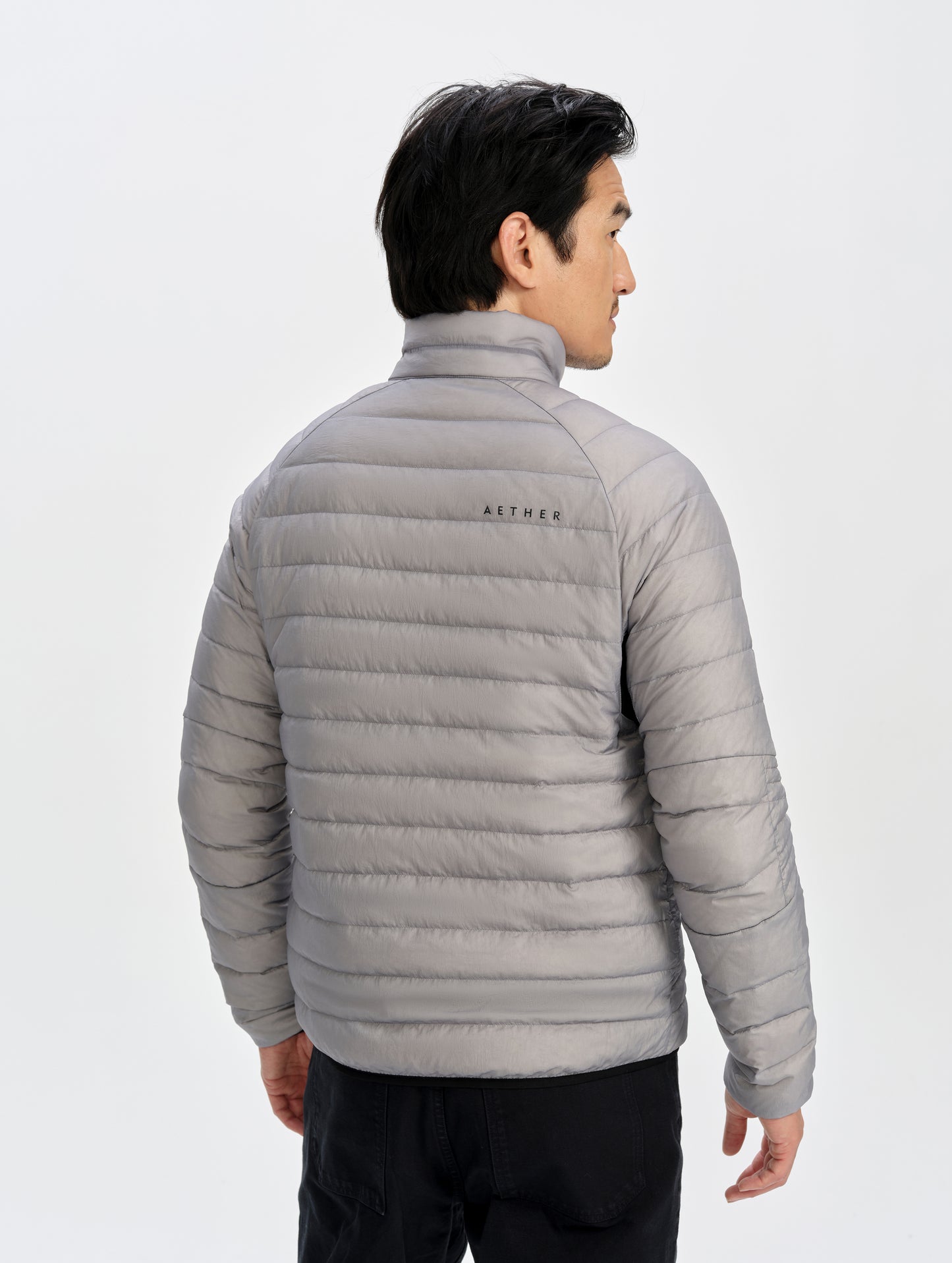 Rear upper-body view of man wearing Prospect Packable Down Jacket in Sky Grey from AETHER Apparel.