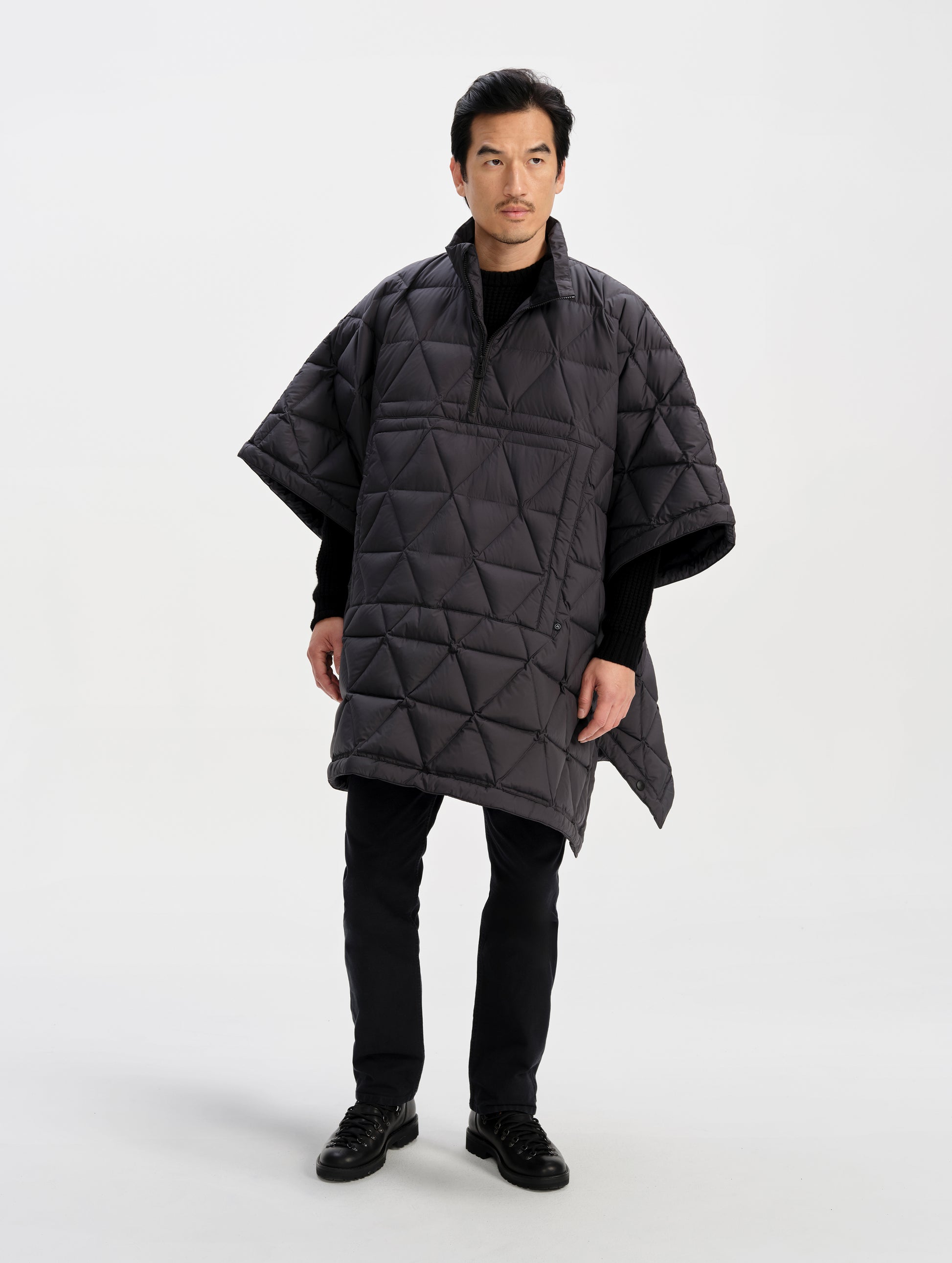 Front full-body view of man wearing the Reeves Down Poncho in Onyx Black from AETHER Apparel. 