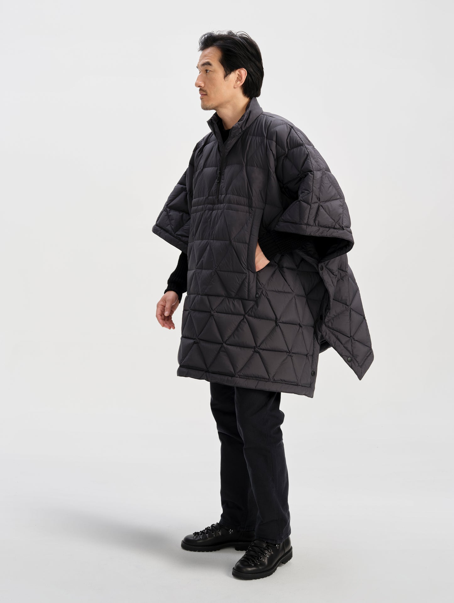 Front 3/4 full-body view of man wearing the Reeves Down Poncho in Onyx Black from AETHER Apparel. 