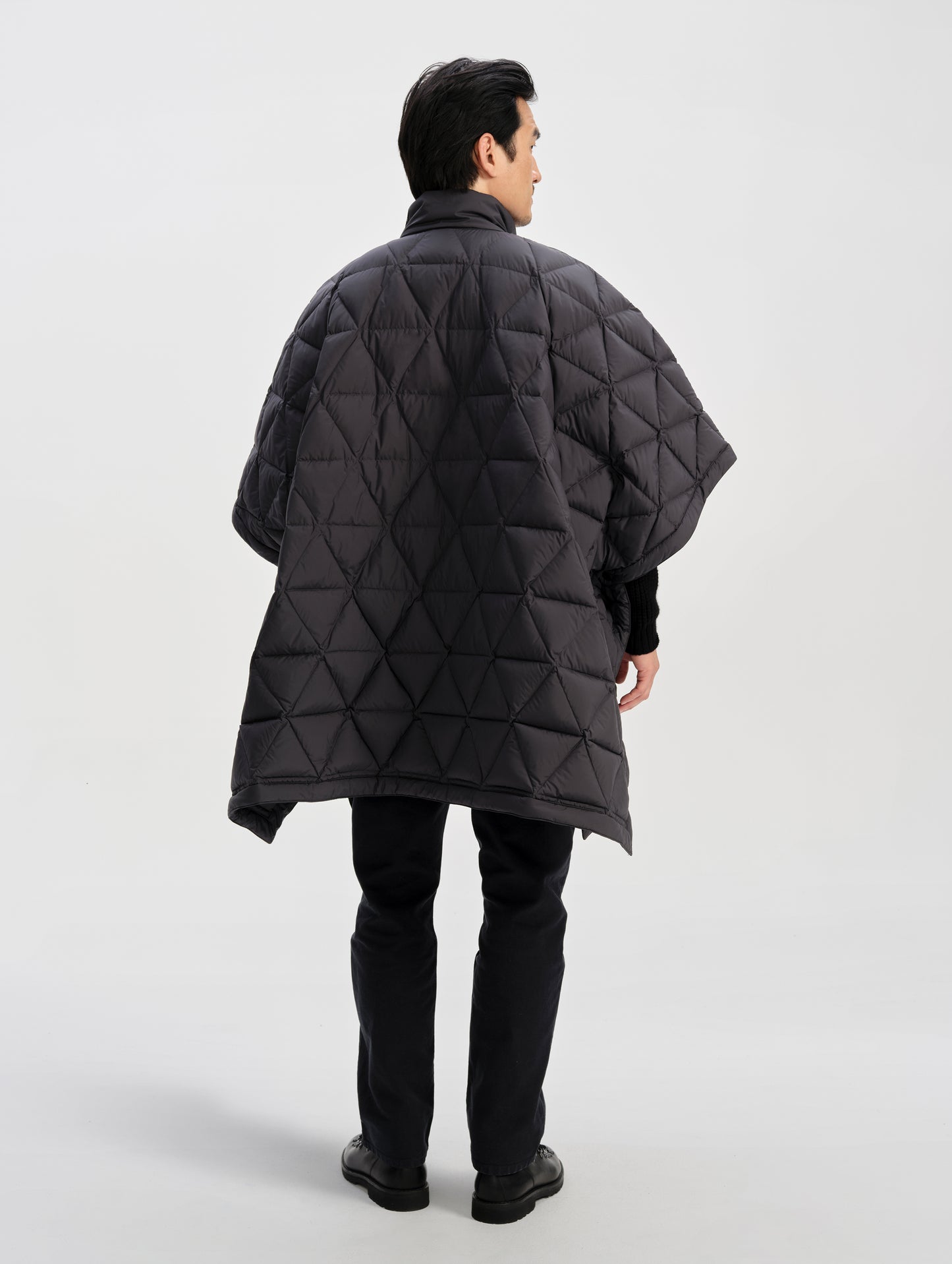 Rear full-body view of man wearing the Reeves Down Poncho in Onyx Black from AETHER Apparel. 