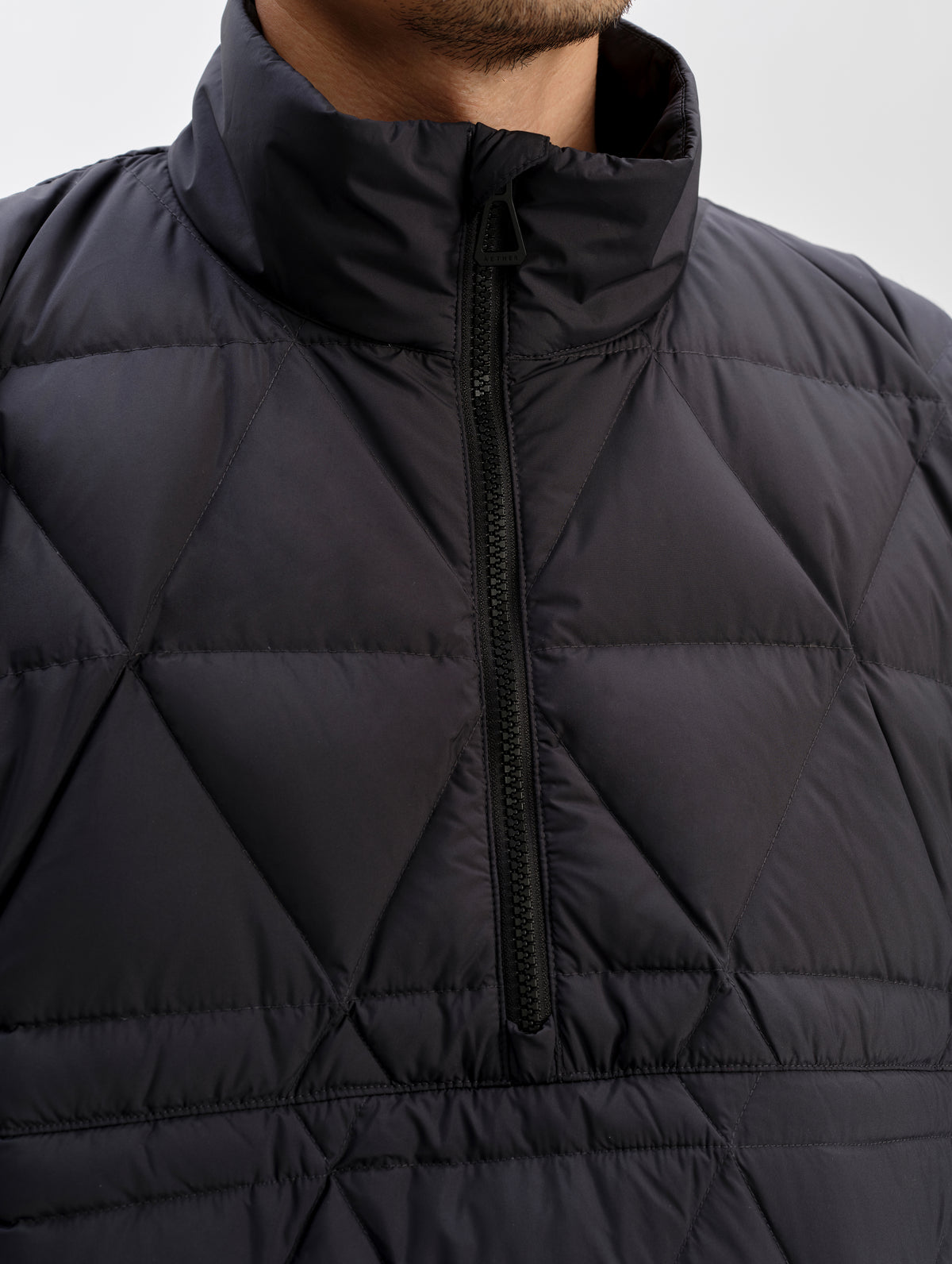 Closeup detailed shot of the center-front half-zip on the Reeves Down Poncho in Onyx Black from AETHER Apparel. 