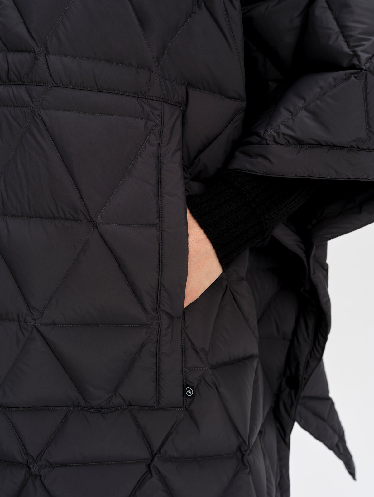 Closeup detailed view of the kangaroo pocket on the Reeves Down Poncho in Onyx Black from AETHER Apparel. 