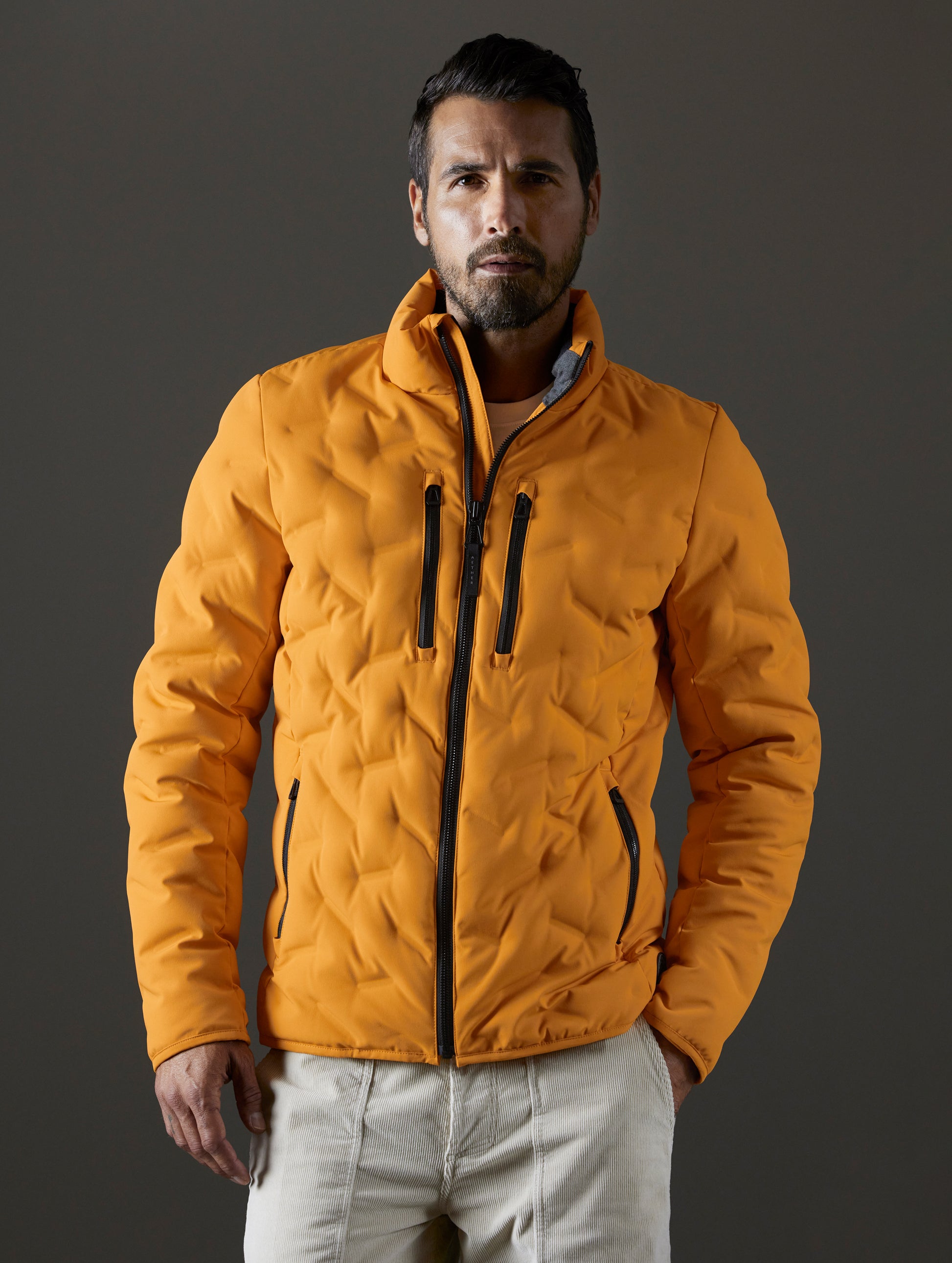 Front body view of man wearing Rex Down Jacket in Midas Orange from AETHER Apparel.