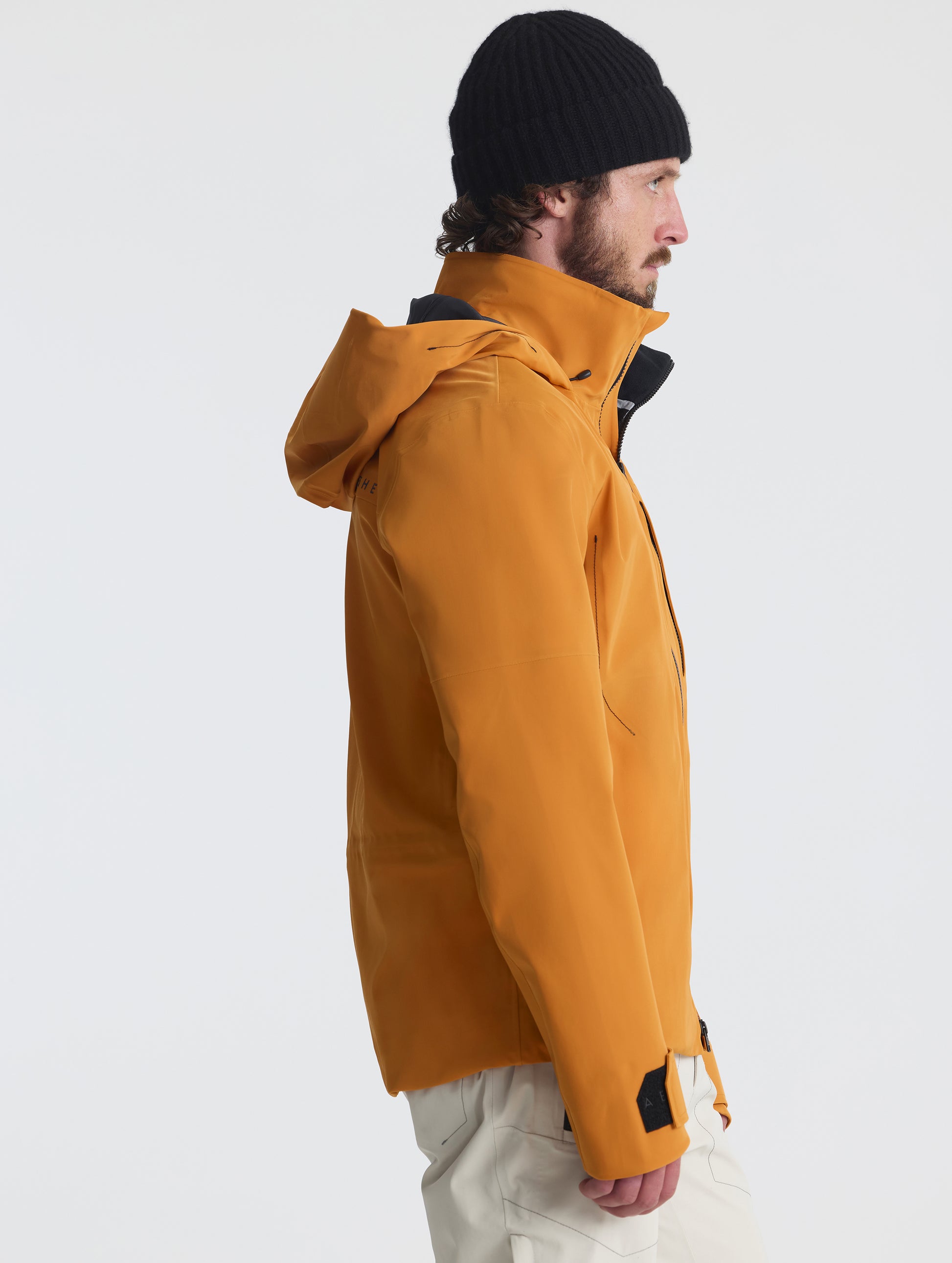 Side profile upper-body view of man wearing the Ridge Snow-Shell Jacket in Autumn Orange from AETHER Apparel.