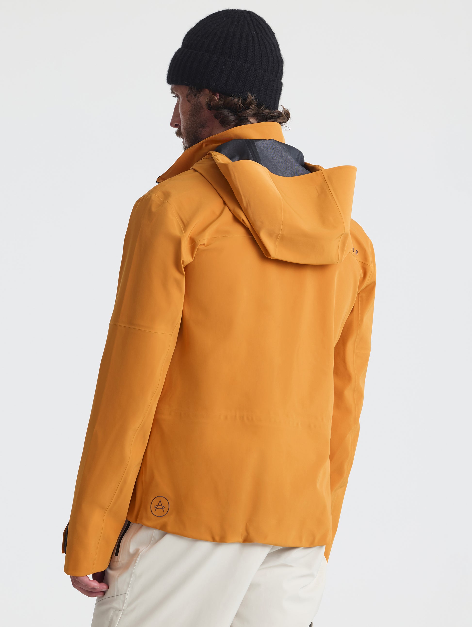 Rear angled upper-body view of man wearing the Ridge Snow-Shell Jacket in Autumn Orange from AETHER Apparel.