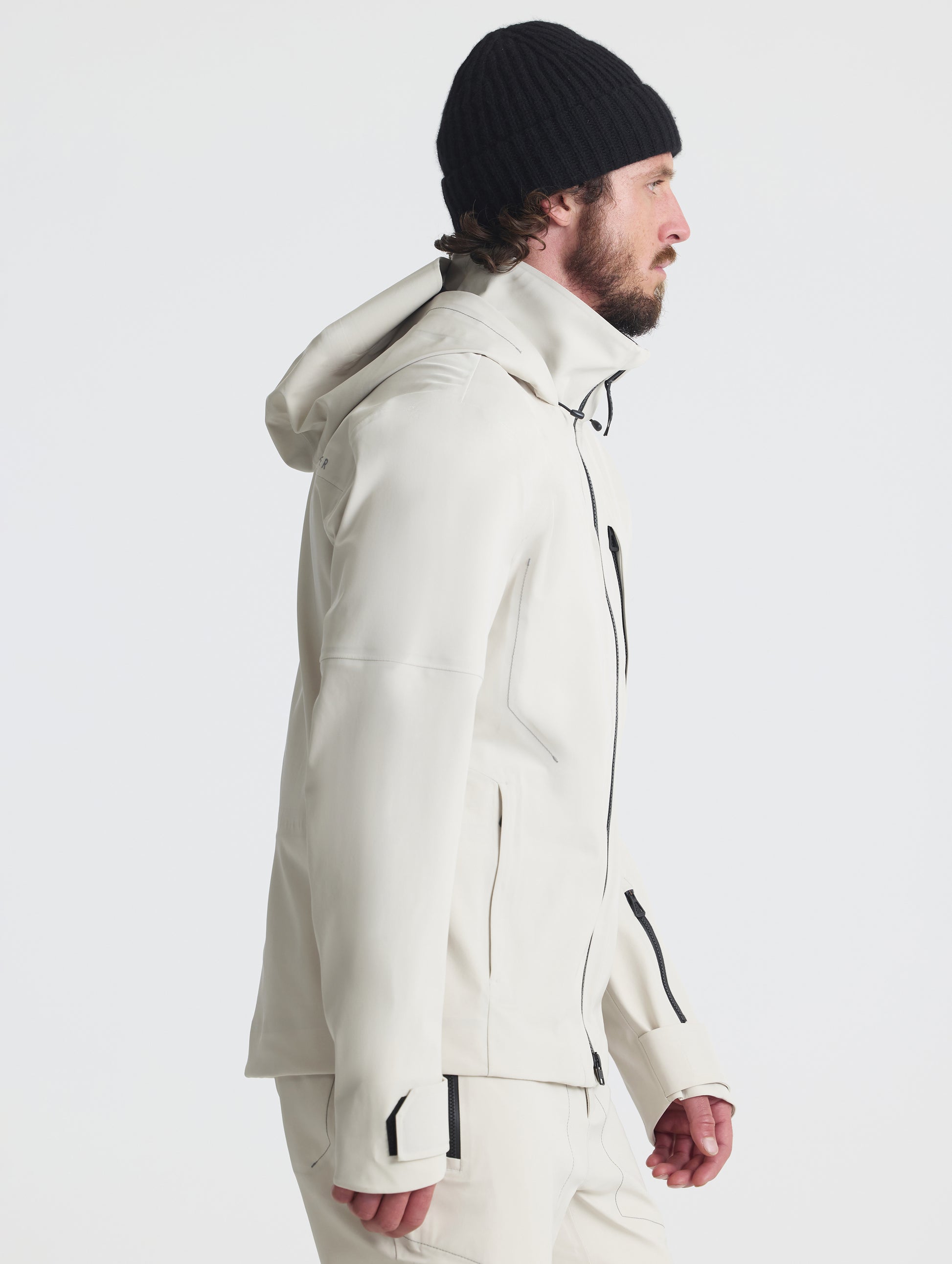 Side profile upper-body view of man wearing the Ridge Snow-Shell Jacket in Bone from AETHER Apparel.