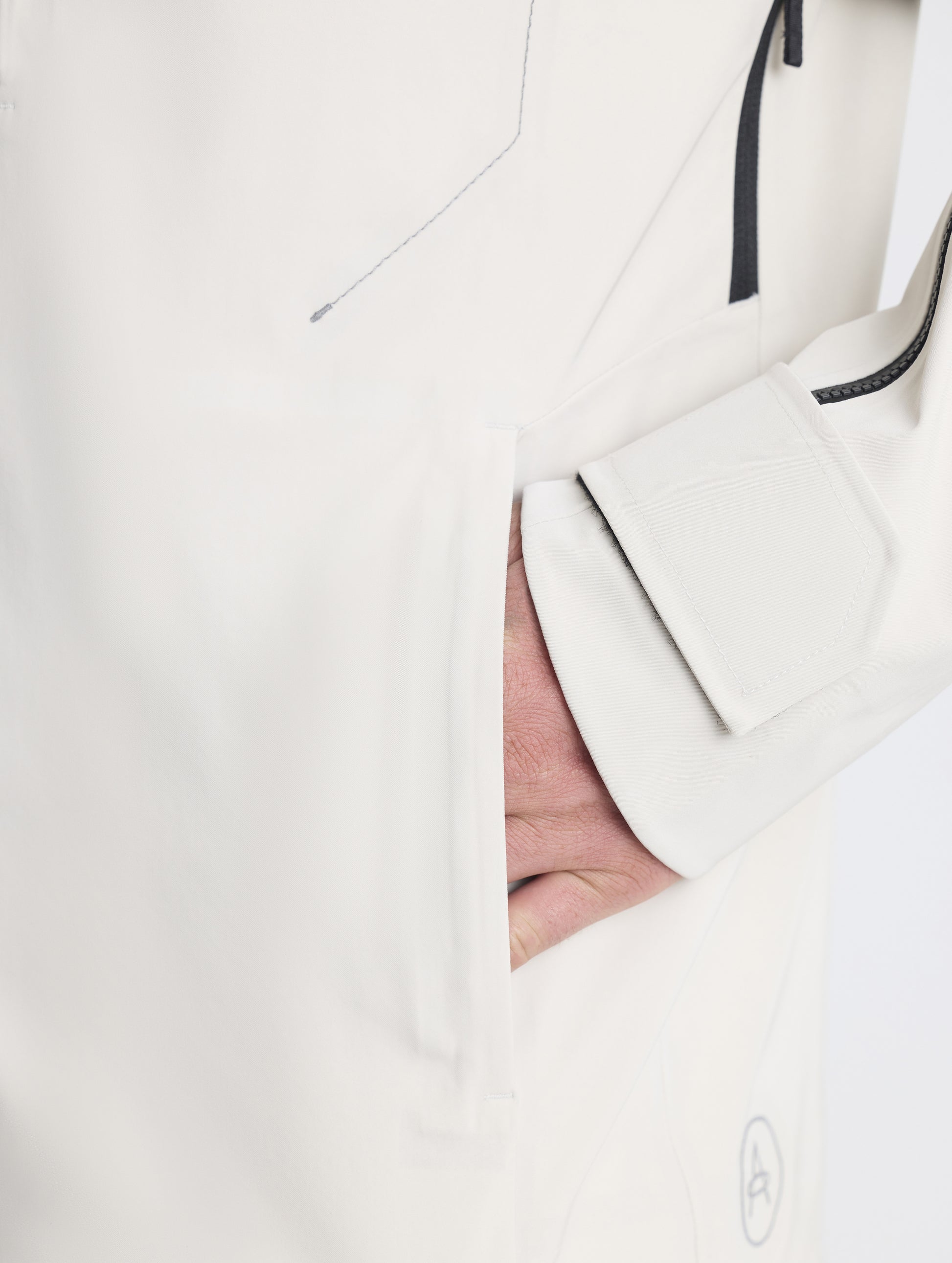 Closeup detailed view of man placing hands into the zipper-secured hand pocket on the Ridge Snow-Shell Jacket in Bone from AETHER Apparel.