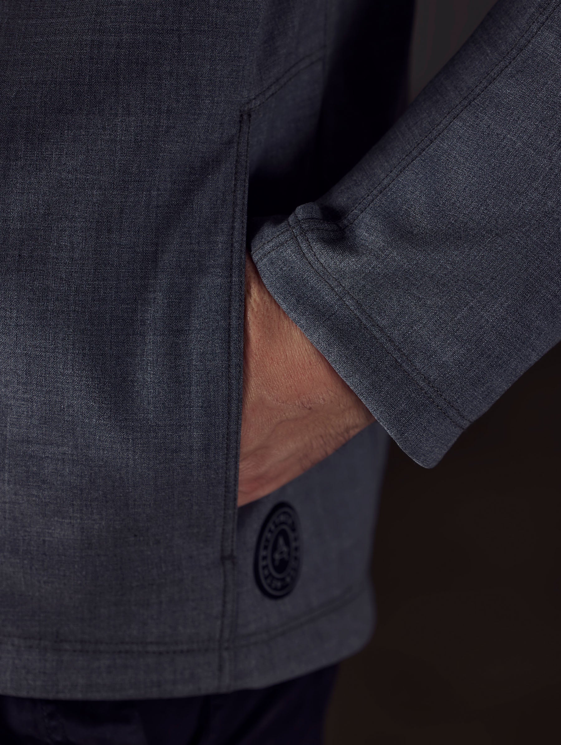 Closeup detailed view of man putting his hand inside the zippered left hand pocket on the Stanton Technical Jacket in Light Heather Grey from AETHER Apparel.
