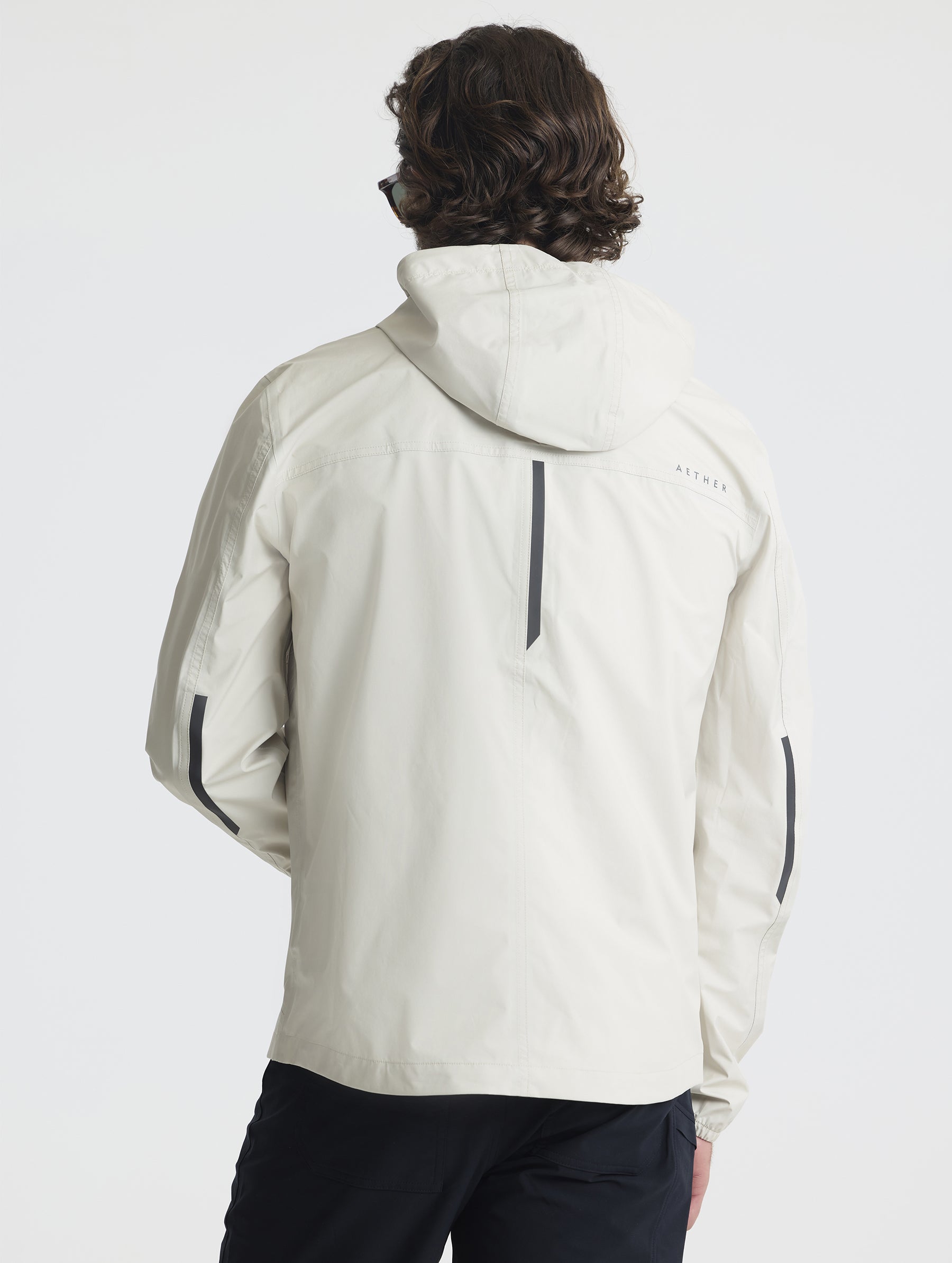 Rear view of man wearing Storm All-Weather Jacket in Bone white from AETHER Apparel.