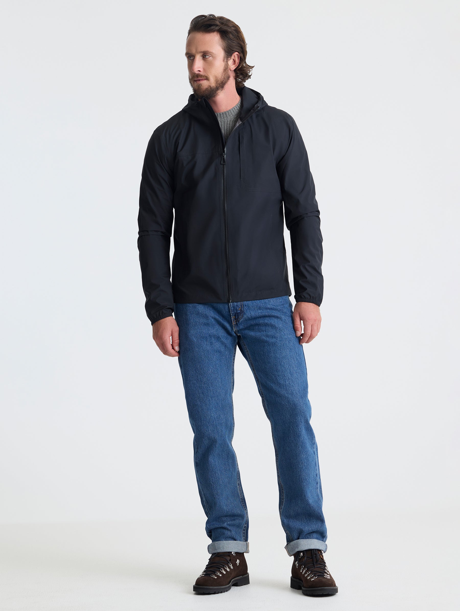 Full body view of man wearing Storm All-Weather Jacket in Onyx Black from AETHER Apparel.