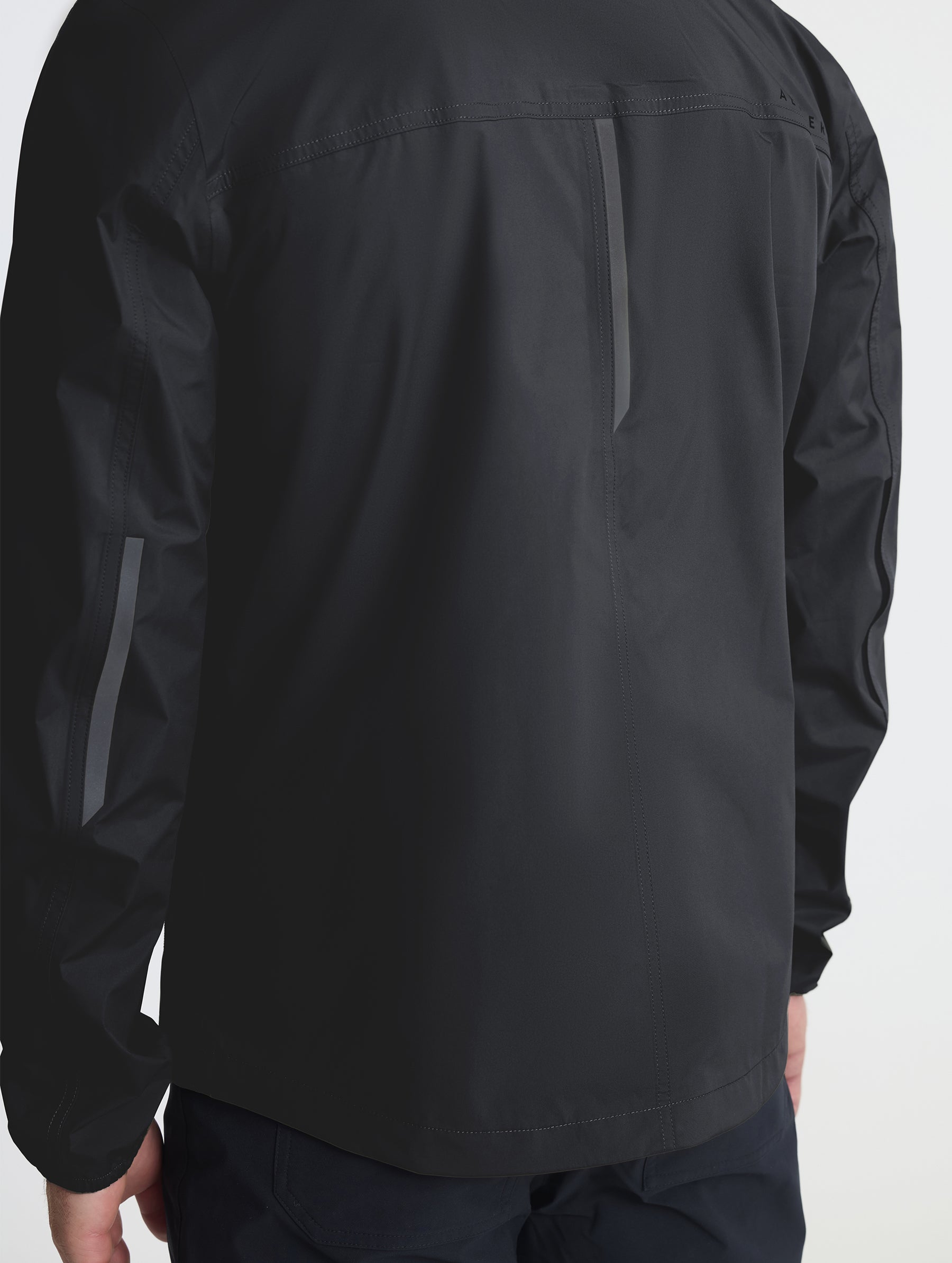 Rear closeup view of self-packing pocket of Storm All-Weather Jacket in Onyx Black from AETHER Apparel.