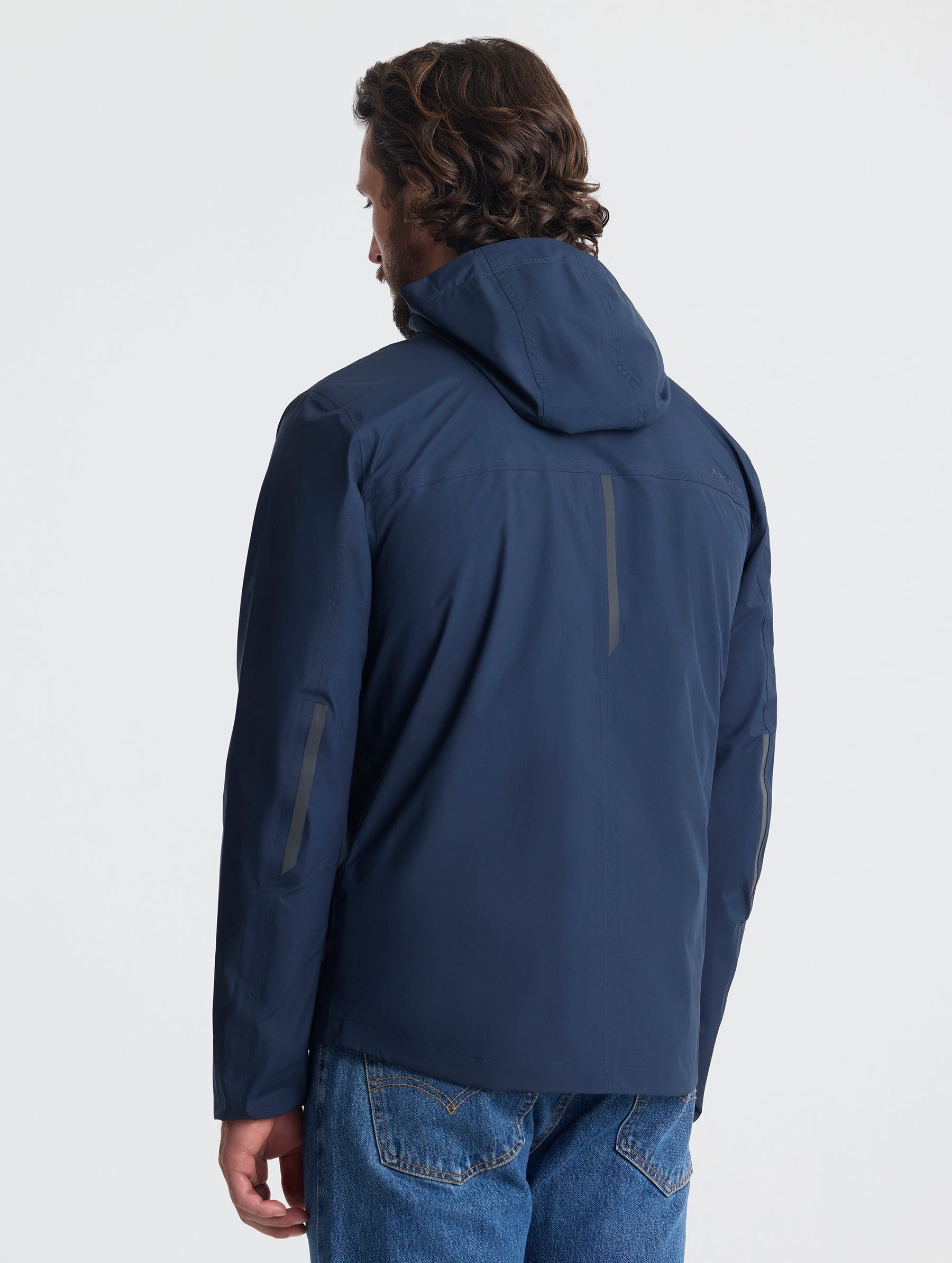 Rear view of man wearing Storm All-Weather Jacket in Total Eclipse dark blue from AETHER Apparel.
