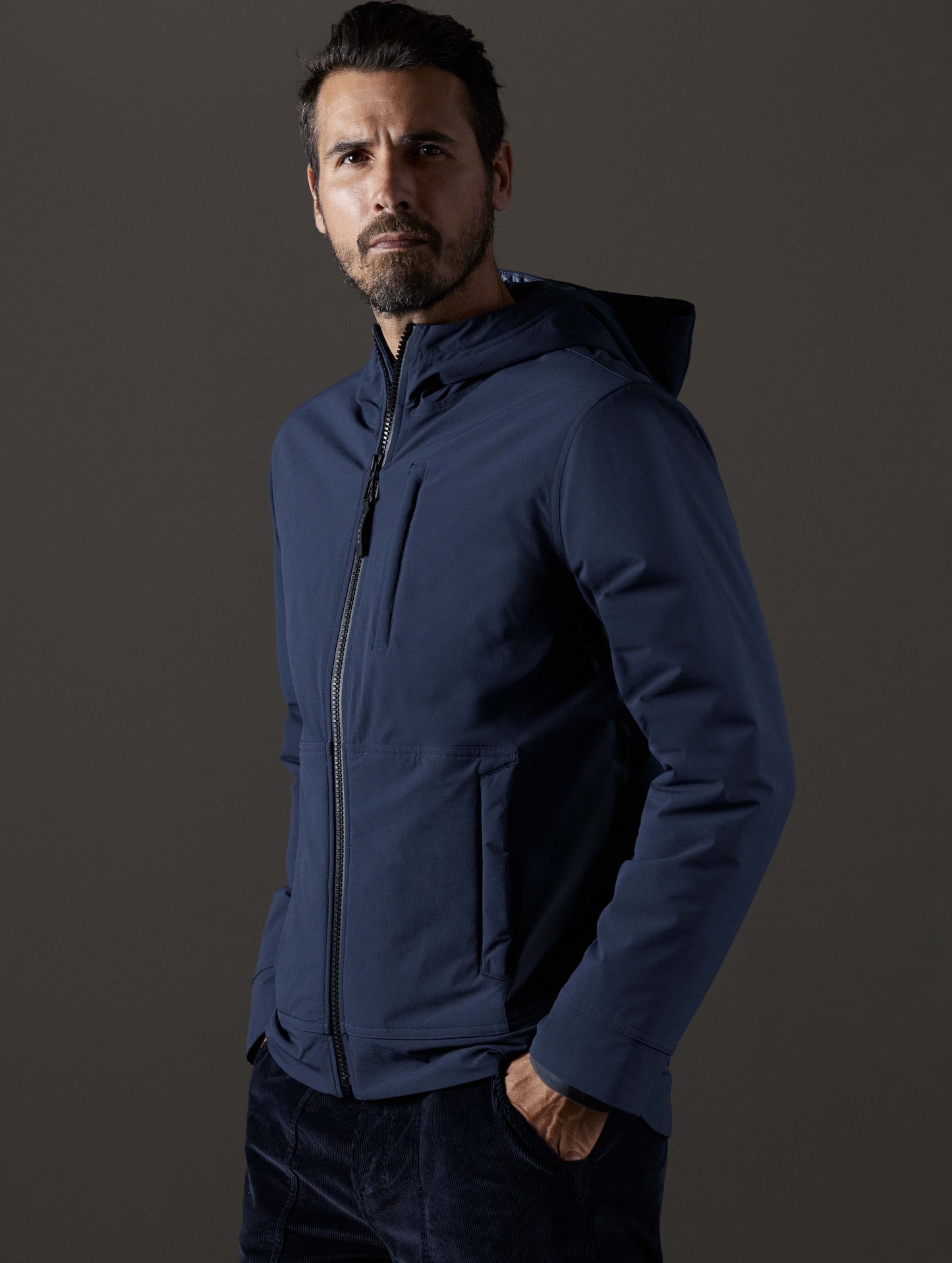 Front 3/4 body view of man wearing Stornaway Insulated Hoodie in Total Eclipse dark blue from AETHER Apparel.