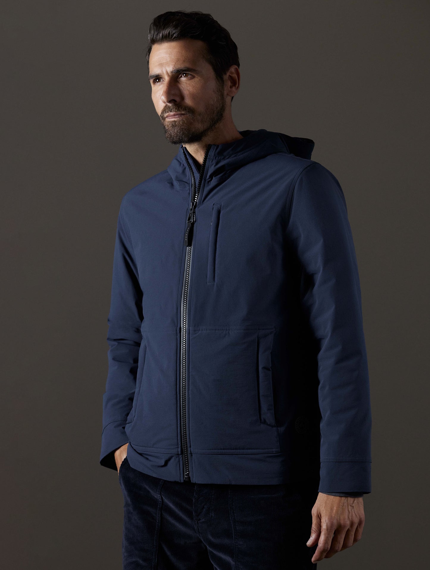 Front body view of man wearing Stornaway Insulated Hoodie in Total Eclipse dark blue from AETHER Apparel.