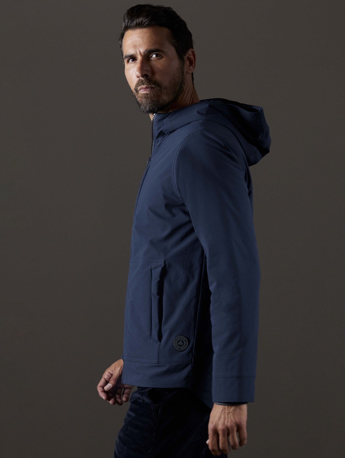 Side profile body view of man wearing Stornaway Insulated Hoodie in Total Eclipse dark blue from AETHER Apparel.