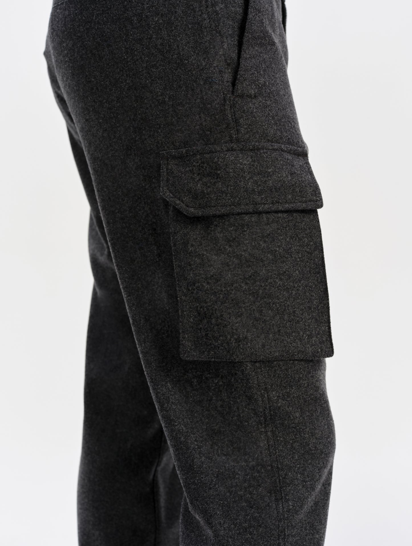 Closeup detailed view of the cargo pockets with hidden button-secured closures on the Strata Wool Pant in Charcoal Heather from AETHER Apparel.