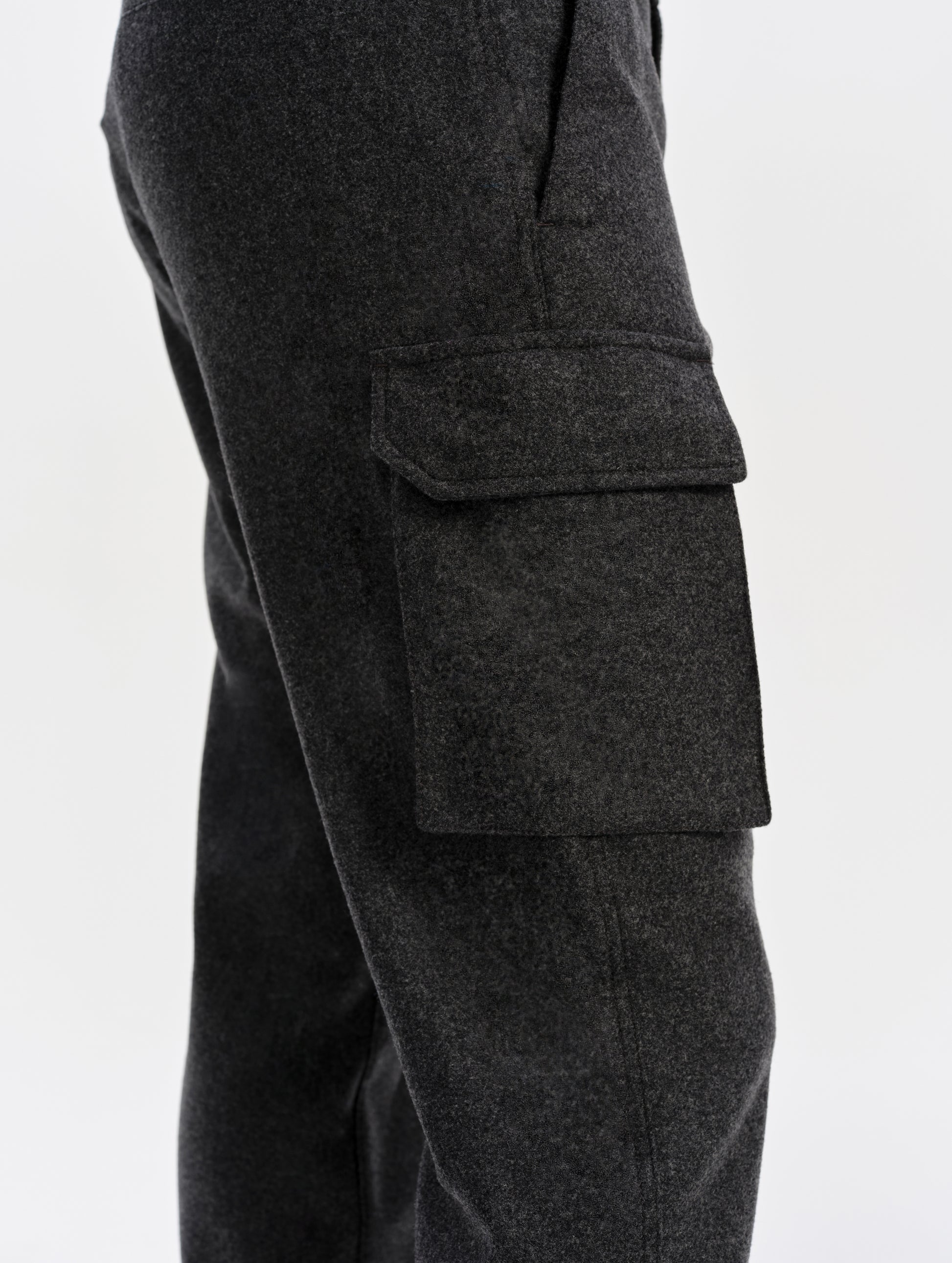 Closeup detailed view of the cargo pockets with hidden button-secured closures on the Strata Wool Pant in Charcoal Heather from AETHER Apparel.