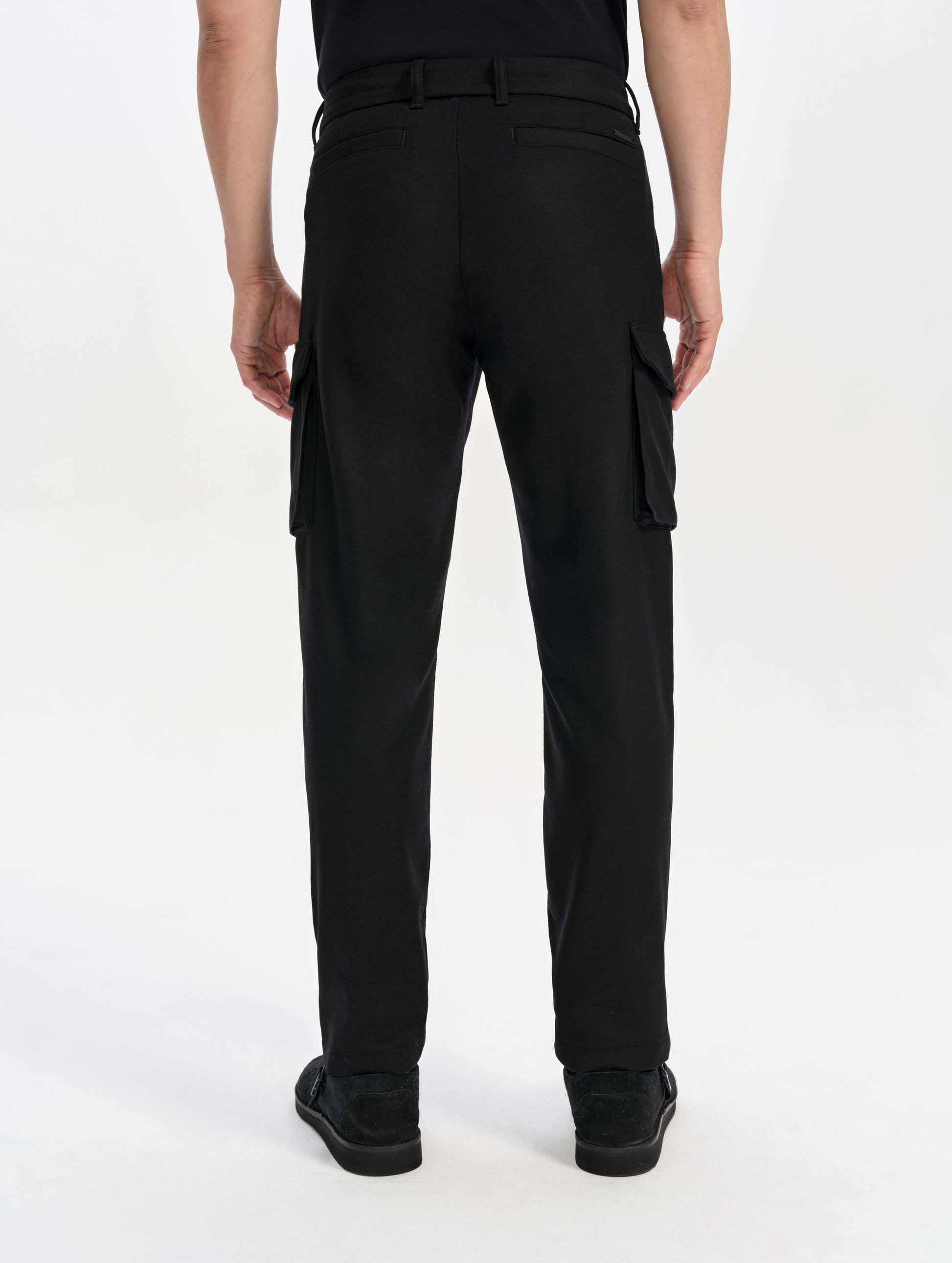 Rear lower-body view of man wearing the Strata Wool Pant in Onyx Black from AETHER Apparel.