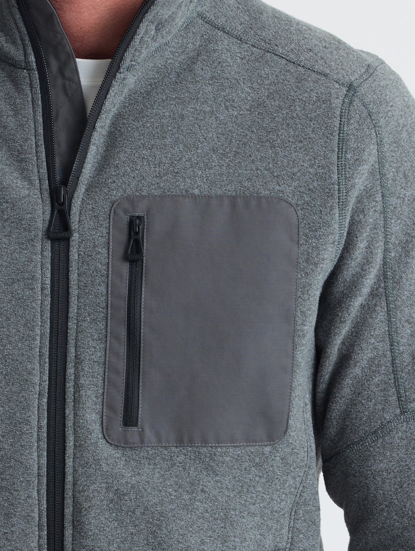 Closeup view of wearer's left shoulder and chest patch of Sutherlin Full-Zip in Charcoal Grey from AETHER Apparel.