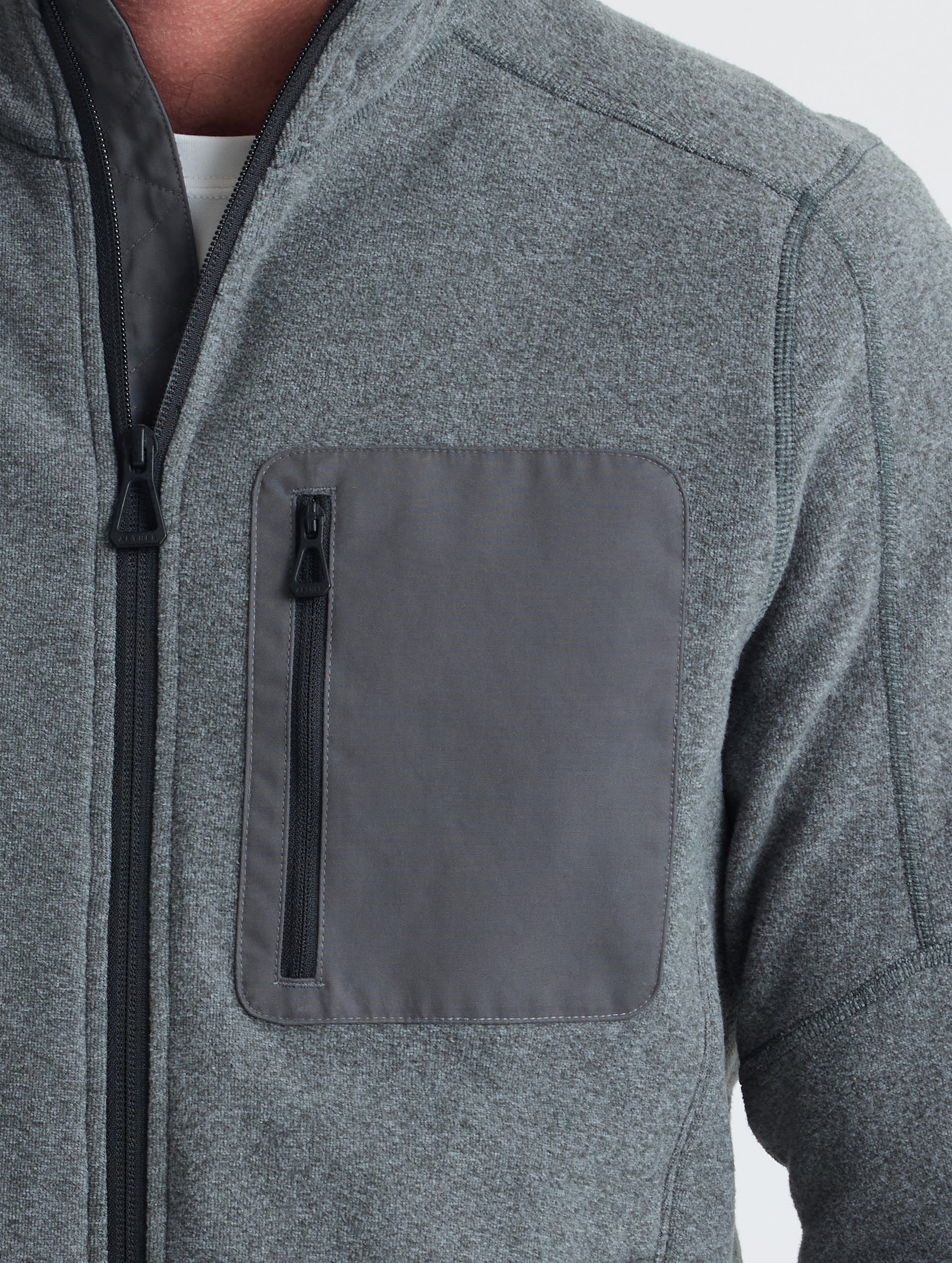 Closeup view of wearer's left shoulder and chest patch of Sutherlin Full-Zip in Charcoal Grey from AETHER Apparel.