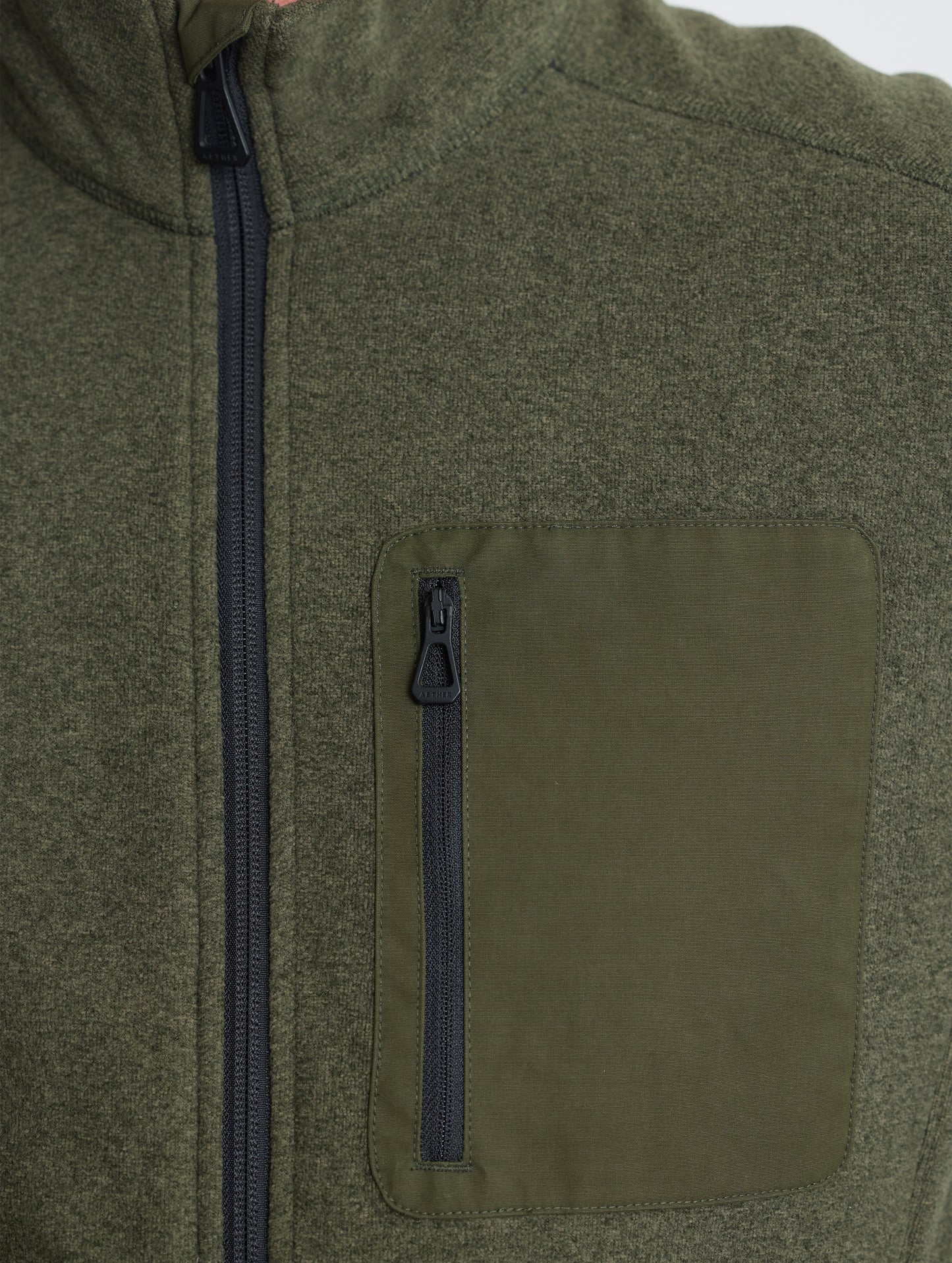 Closeup view of wearer's left shoulder and chest patch of Sutherlin Full-Zip in Forest Green from AETHER Apparel.