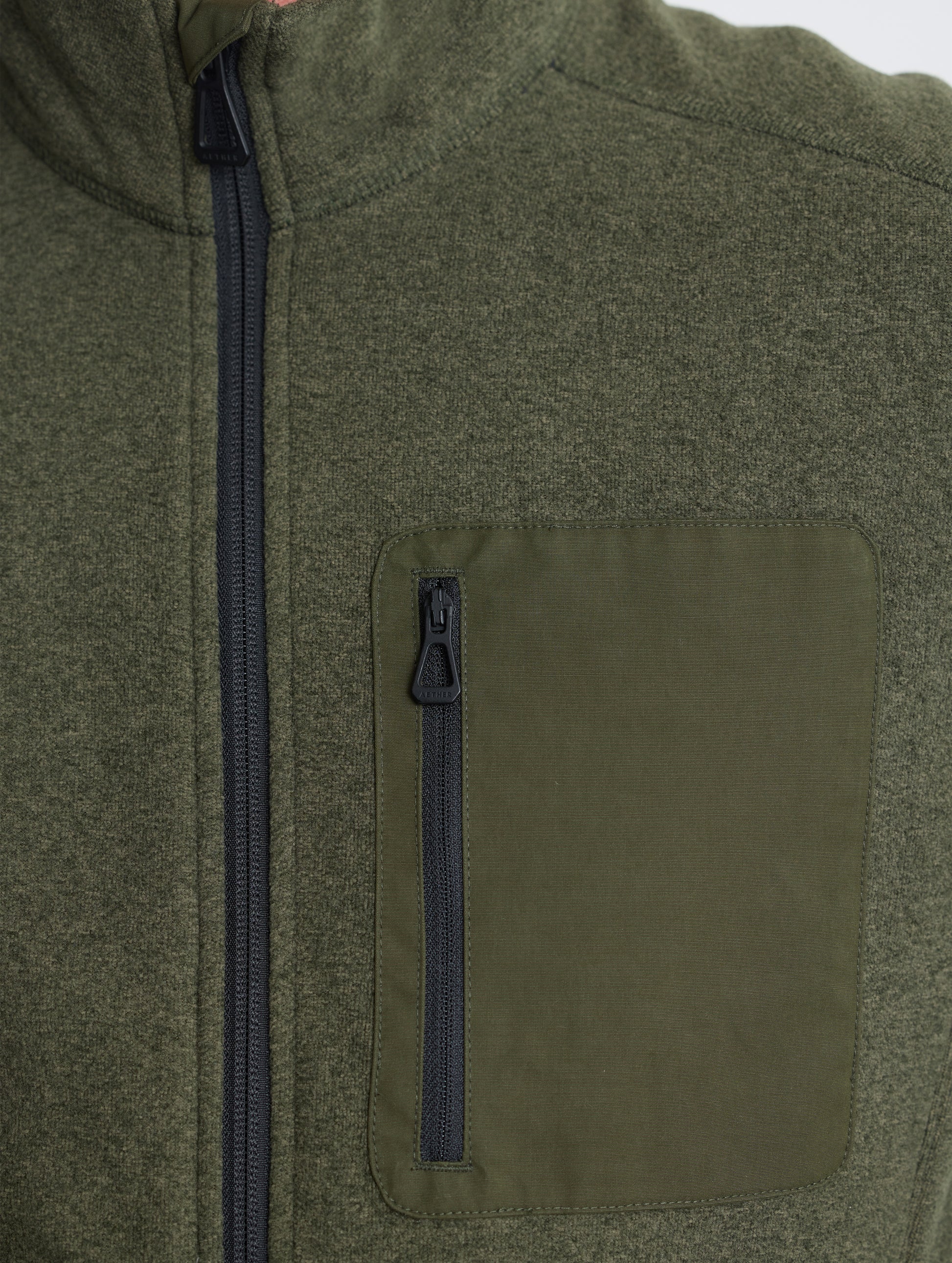 Closeup view of wearer's left shoulder and chest patch of Sutherlin Full-Zip in Forest Green from AETHER Apparel.