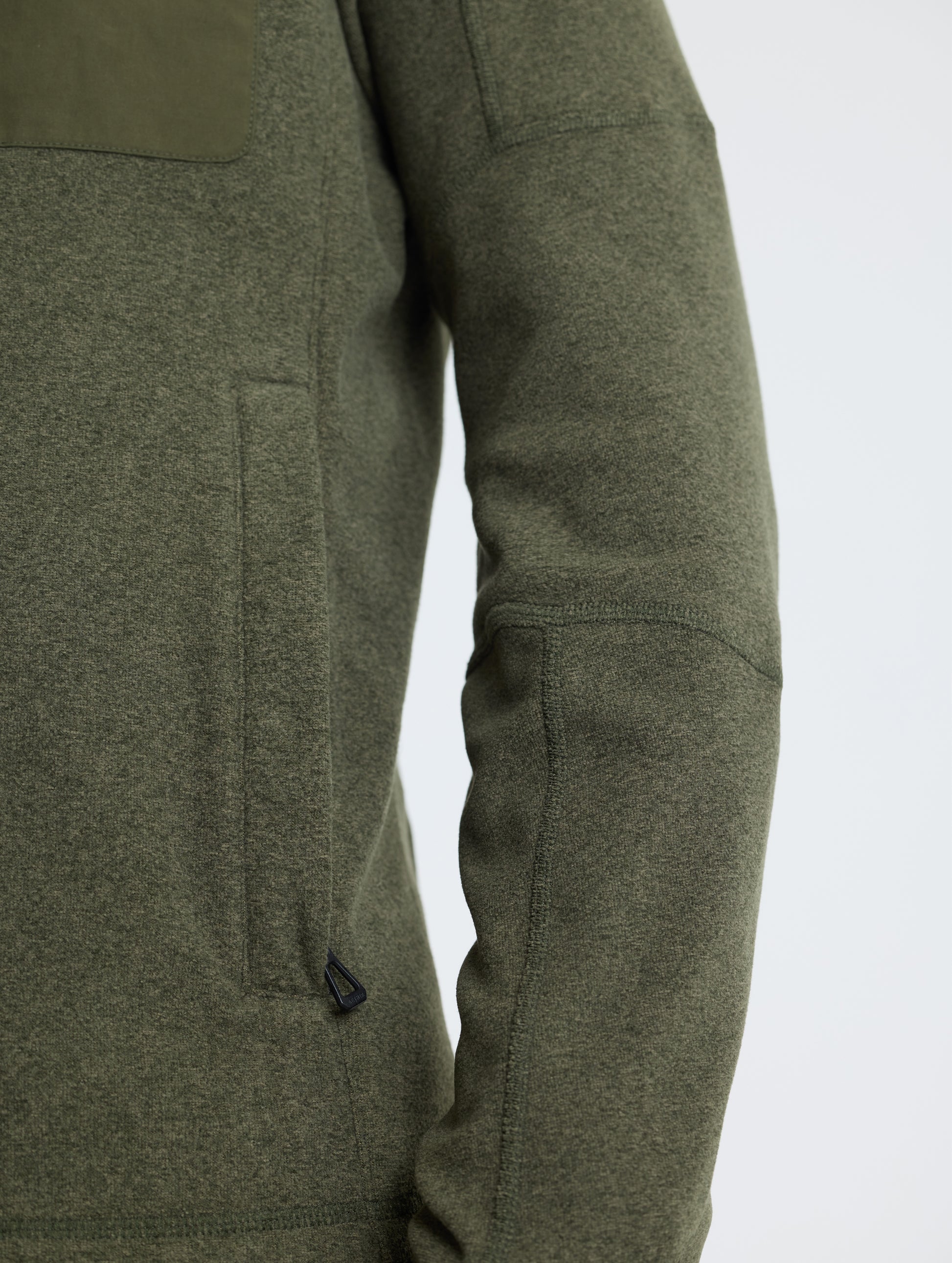 Closeup view of wearer's left hand pocket and sleeve of Sutherlin Full-Zip in Forest Green from AETHER Apparel.