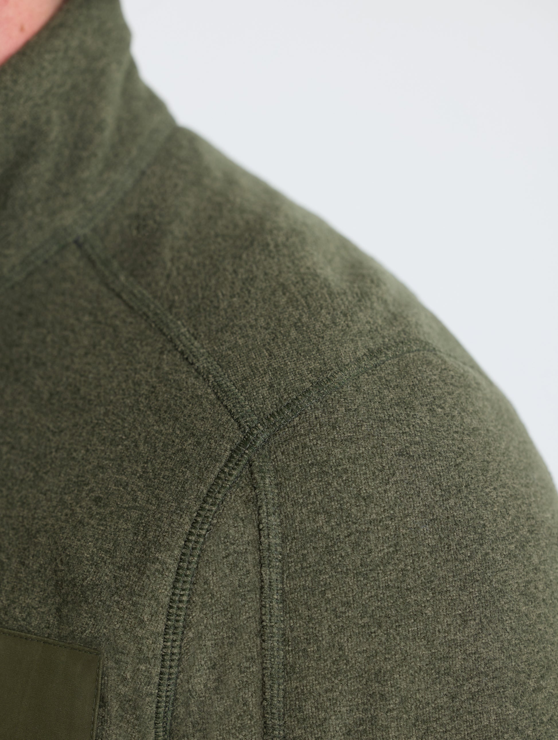 Closeup detail view of wearer's left shoulder of Sutherlin Full-Zip in Forest Green from AETHER Apparel.